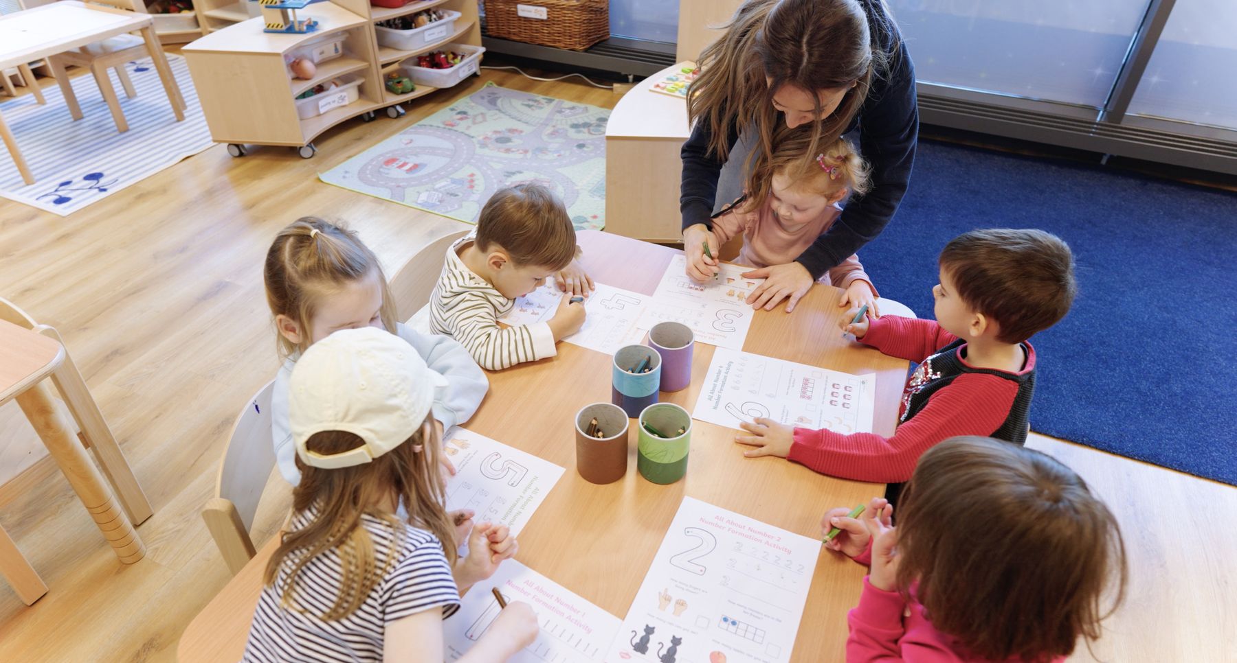 Lehrerin mit Kindern beim Zahlenüben in der Kita Zug
