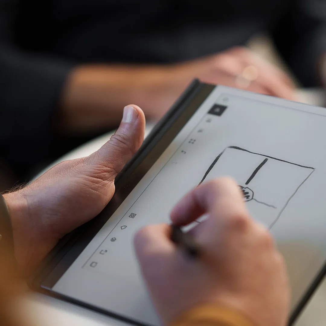 Person som skissar en idé på en digital skrivplatta under ett möte – symbol för kreativt samarbete och strategiarbete.