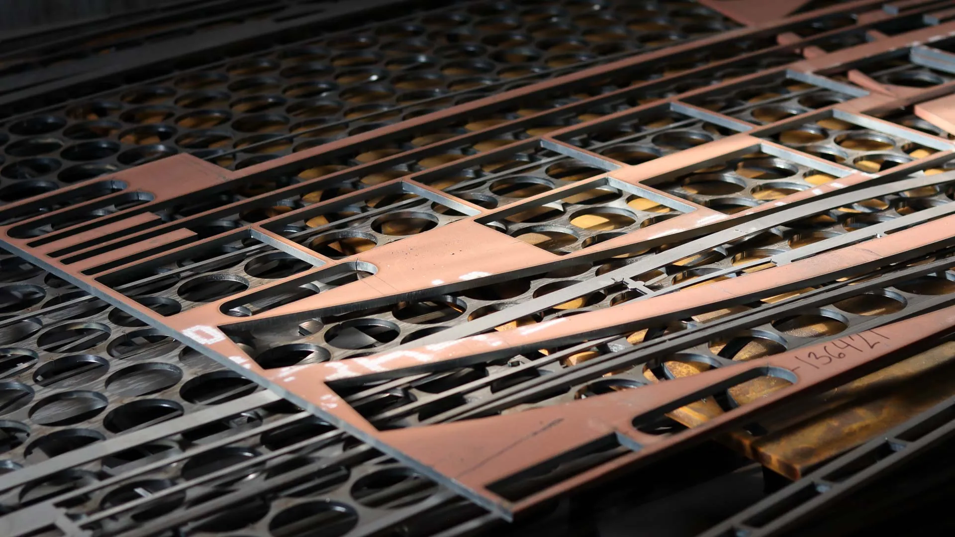 Närbild av utskurna metallplåtar med geometriska former liggande i lager.