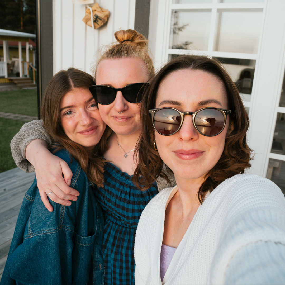 Tre personer håller om varandra och ler in i kameran