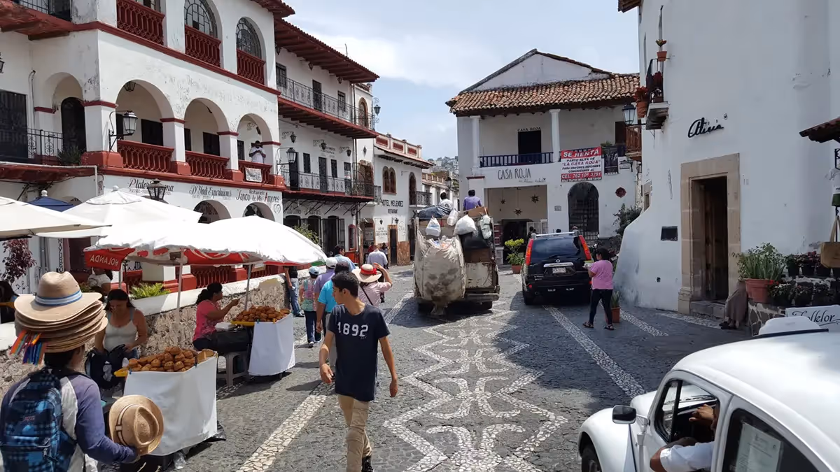 Busy street in Taxco with people, shops, and cars