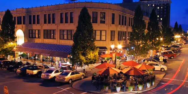 Same large building surrounded by cars and lights and shops