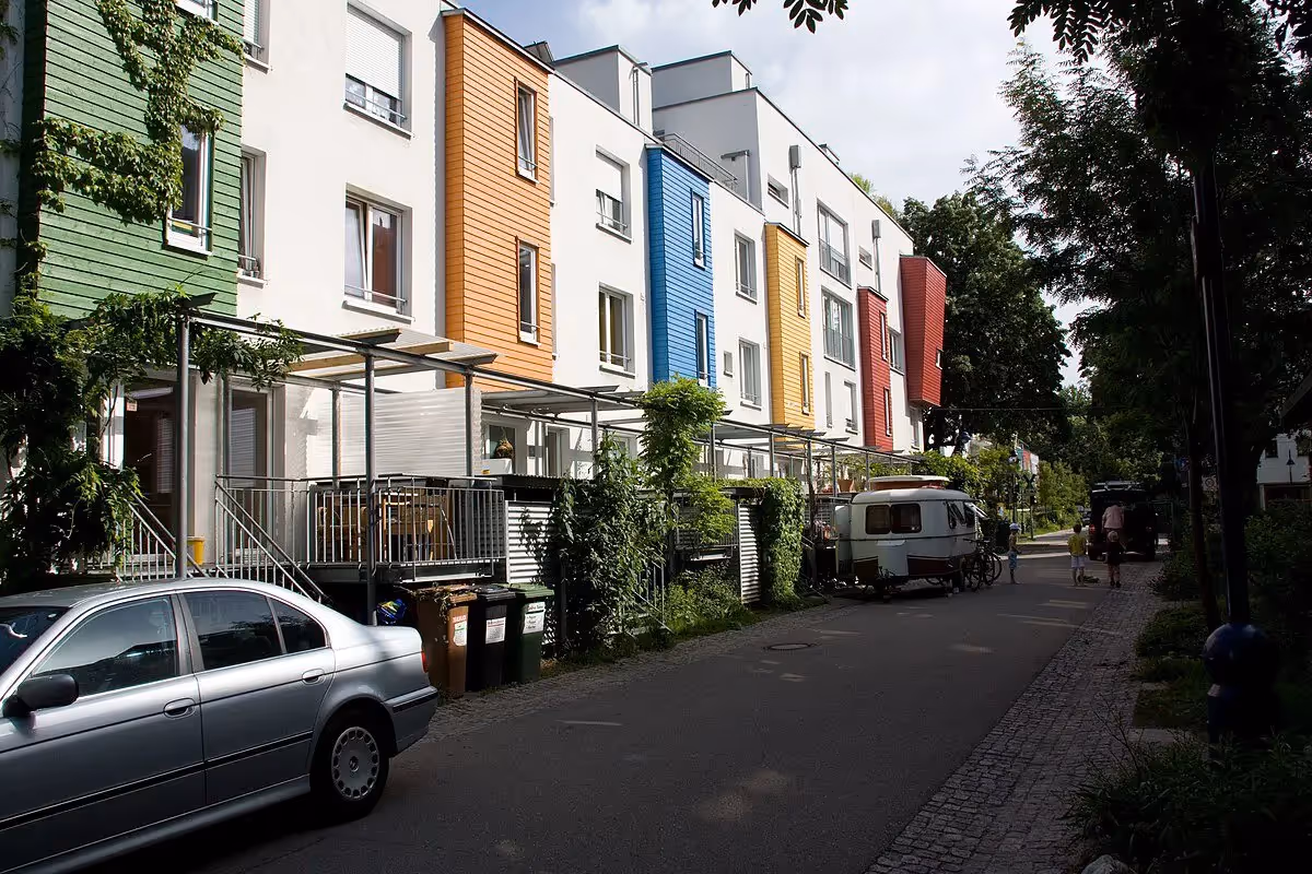 Row of colorful homes with narrow street and parked cars
