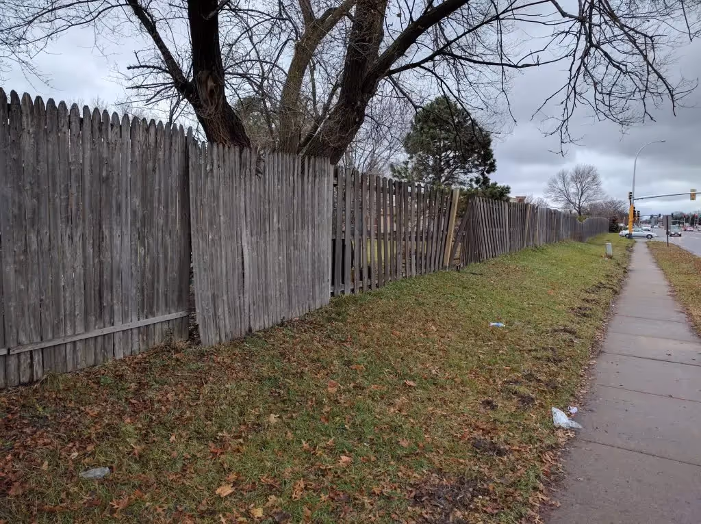 Sidewalk bordered with uninteresting fence