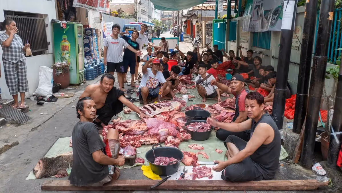 People sitting on street and cutting raw meat together