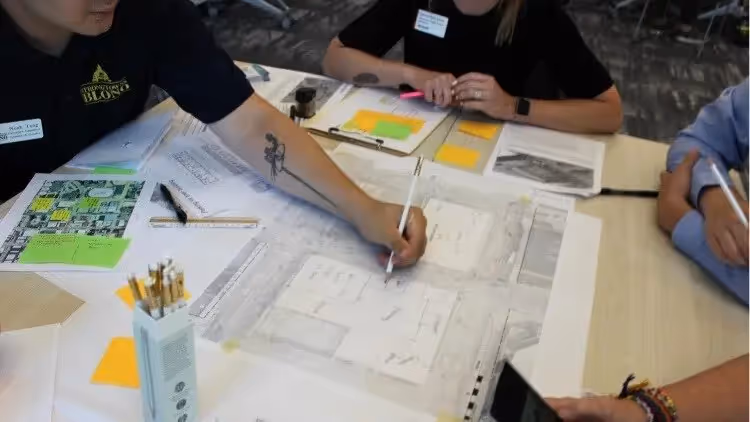 Closeup of people working on diagrams with papers scattered on a table