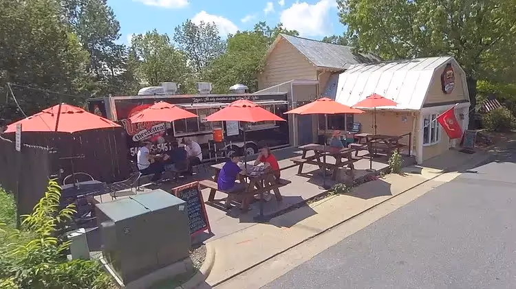 Same house on the street now filling the lot with a food truck and tables for people to eat at