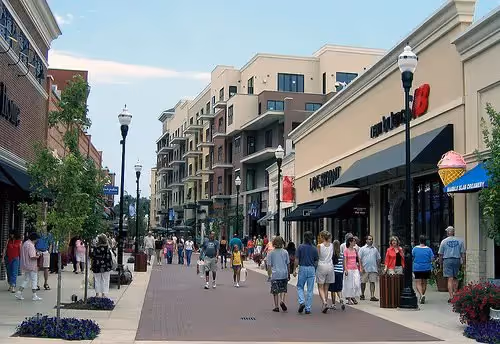 People walking down a commercial street with apartments in the background
