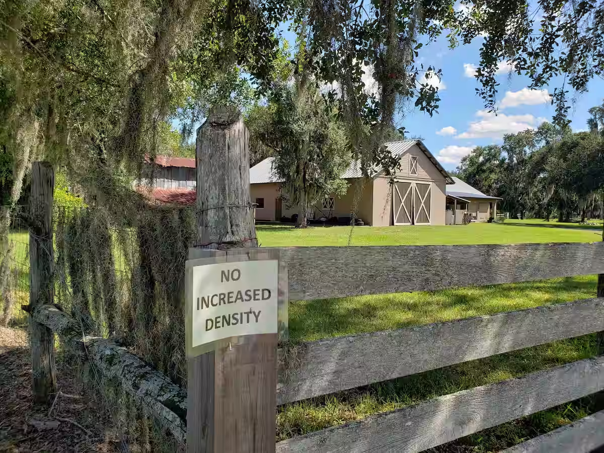 Rustic barn building with a wooden fence with a sign saying no increased density