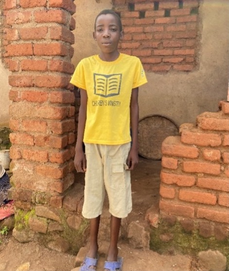 Youth in yellow book-themed shirt standing in front of brick wall