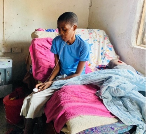 Person in blue shirt sitting on bed with colorful blankets and pillows