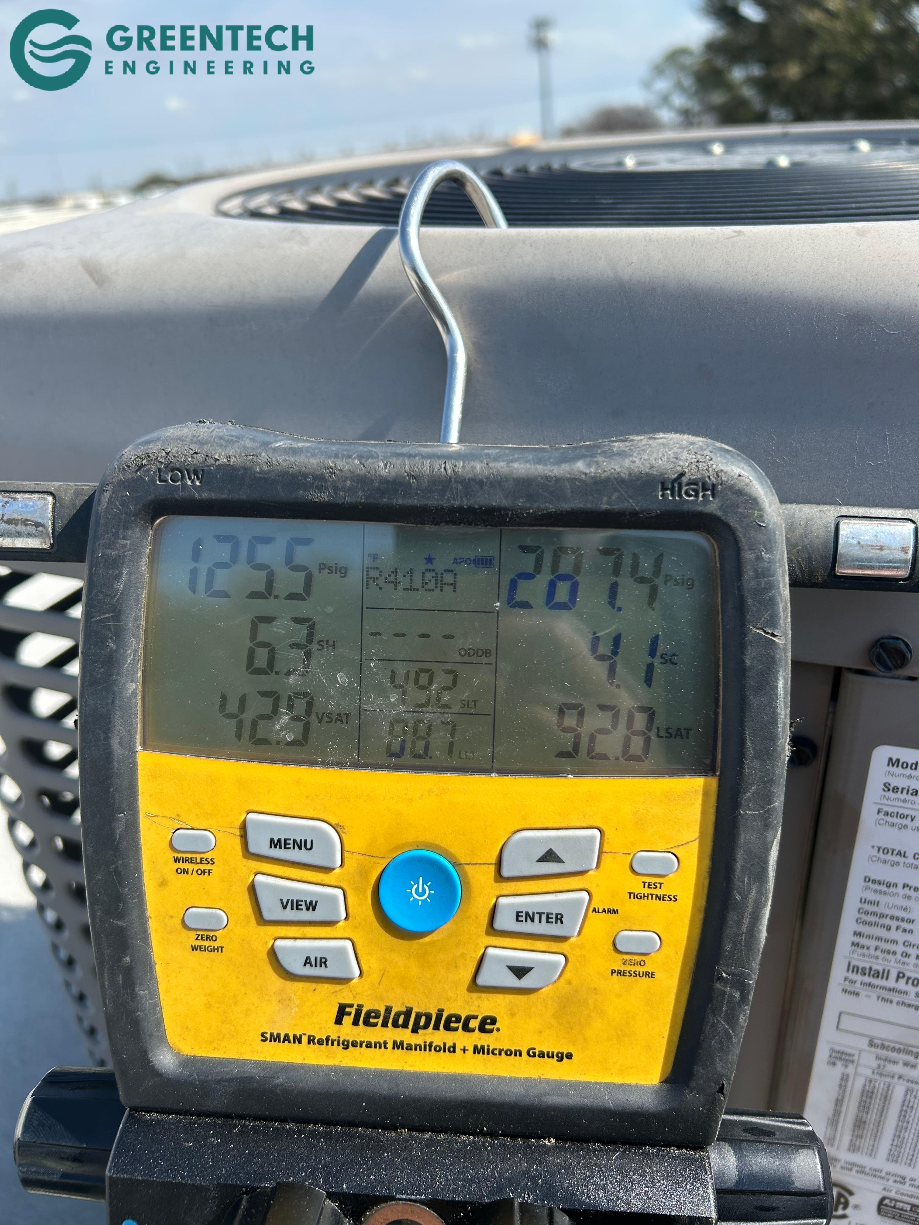 Greentech Engineering technician using Fieldpiece digital manifold gauges to verify correct AC refrigerant pressures after a repair in Grand Prairie, Texas.
