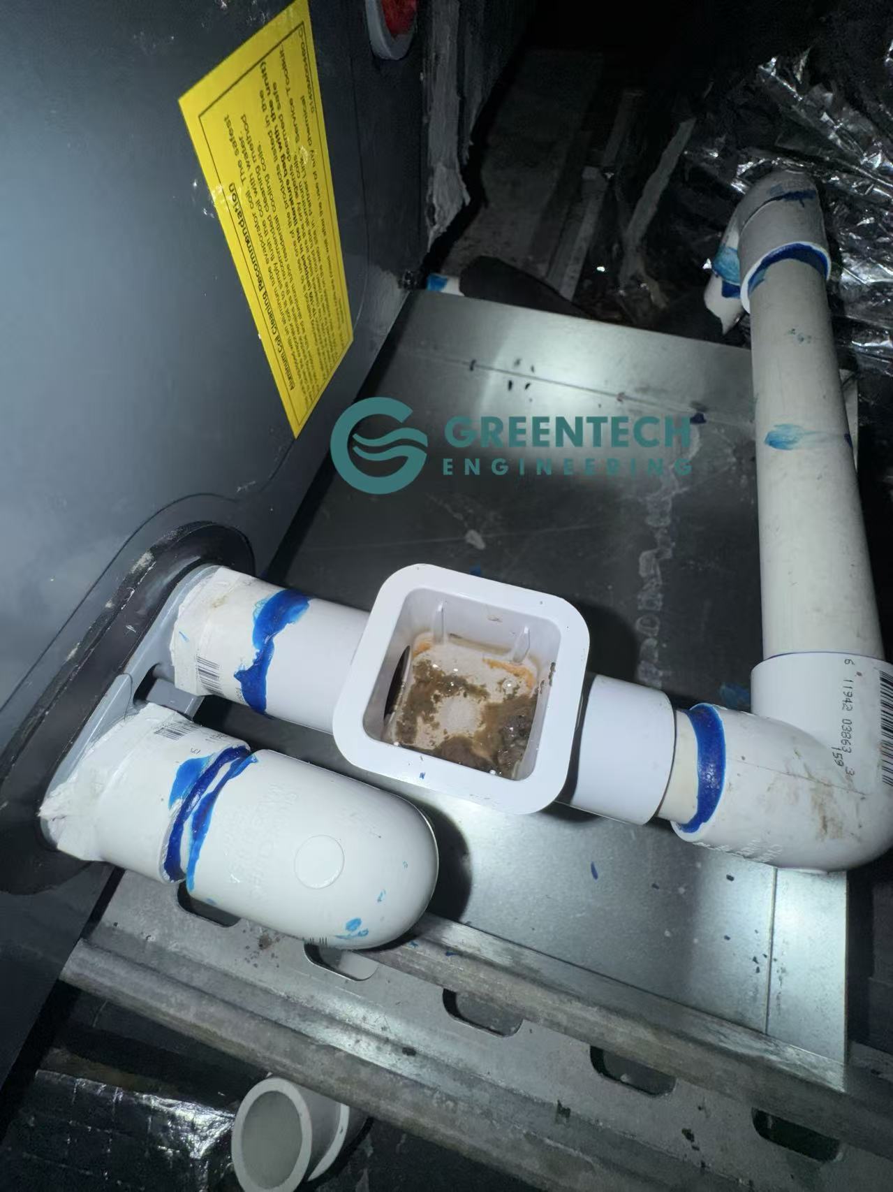 A severely clogged HVAC condensate drain line filled with sludge, posing a major water leak risk for the ceiling below.