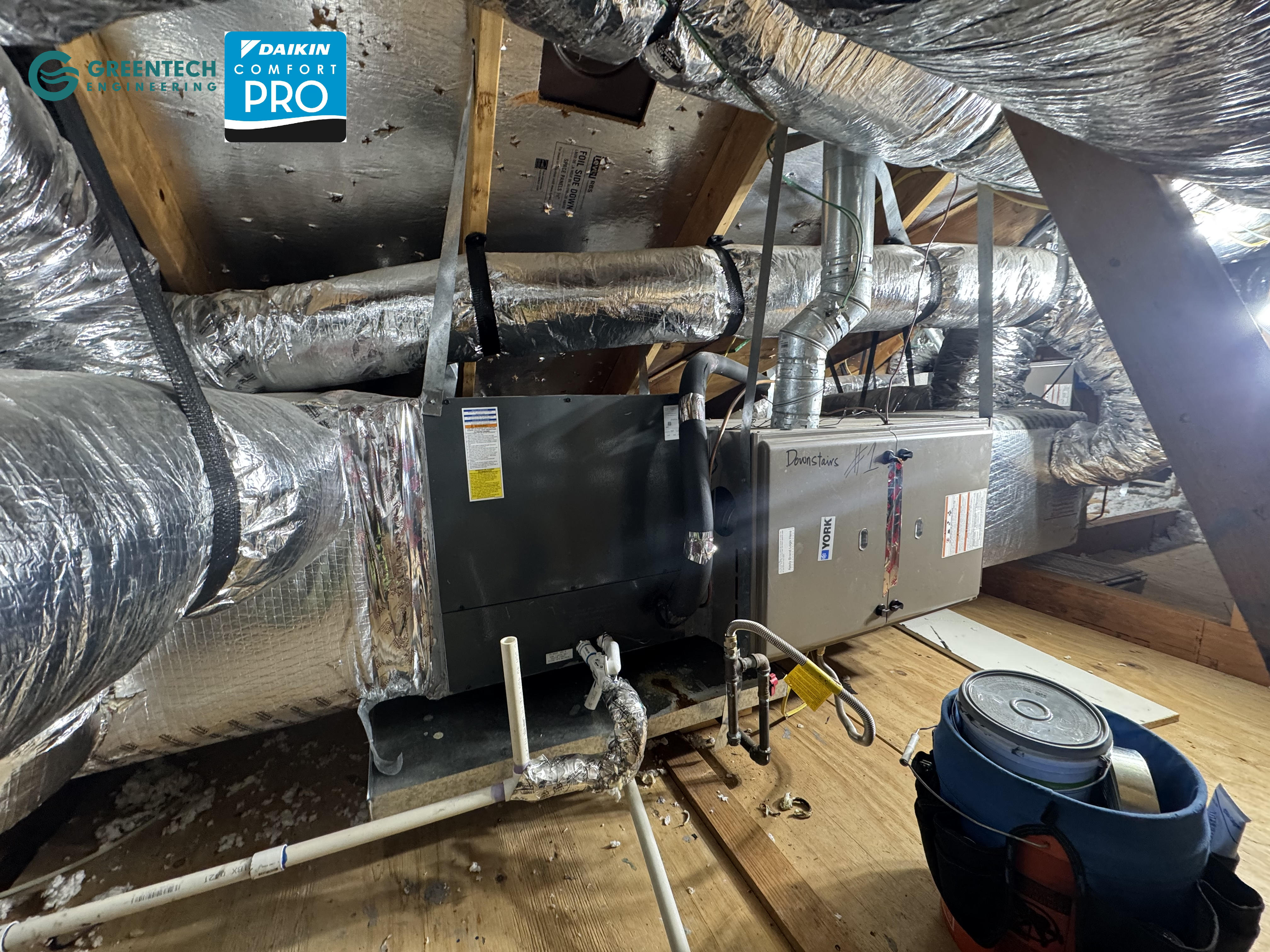 An old York gas furnace installed horizontally in a residential attic with foil-backed insulation.