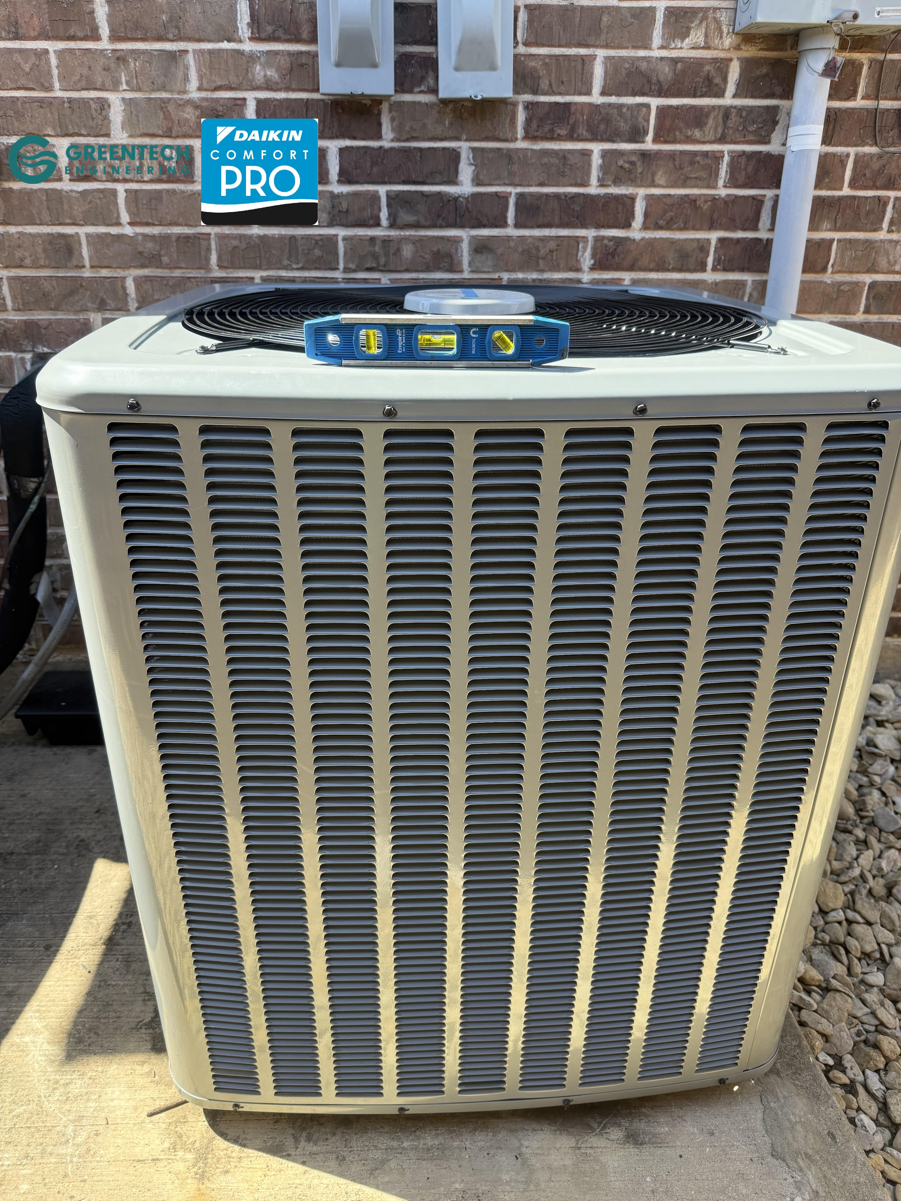 A torpedo level sitting on top of a new Daikin air conditioning condenser unit, showing perfect balance.