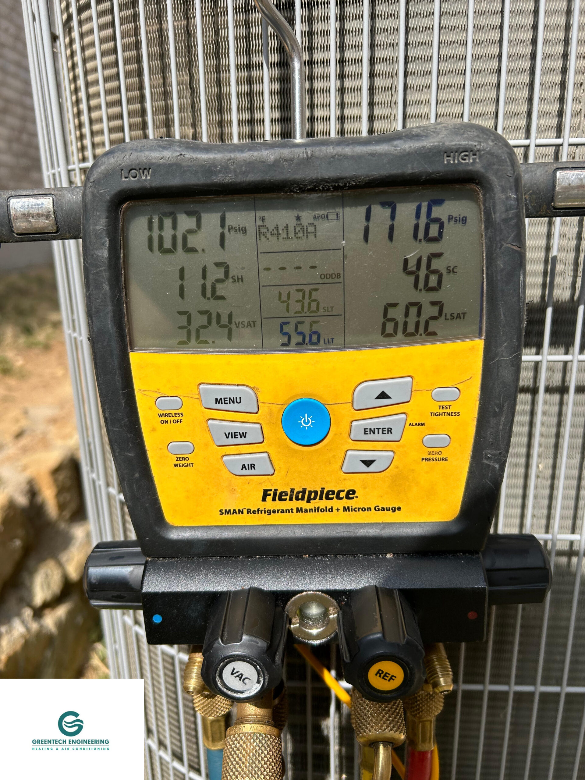 Greentech Engineering technician using a Fieldpiece digital manifold gauge during an AC repair in Grand Prairie, TX.