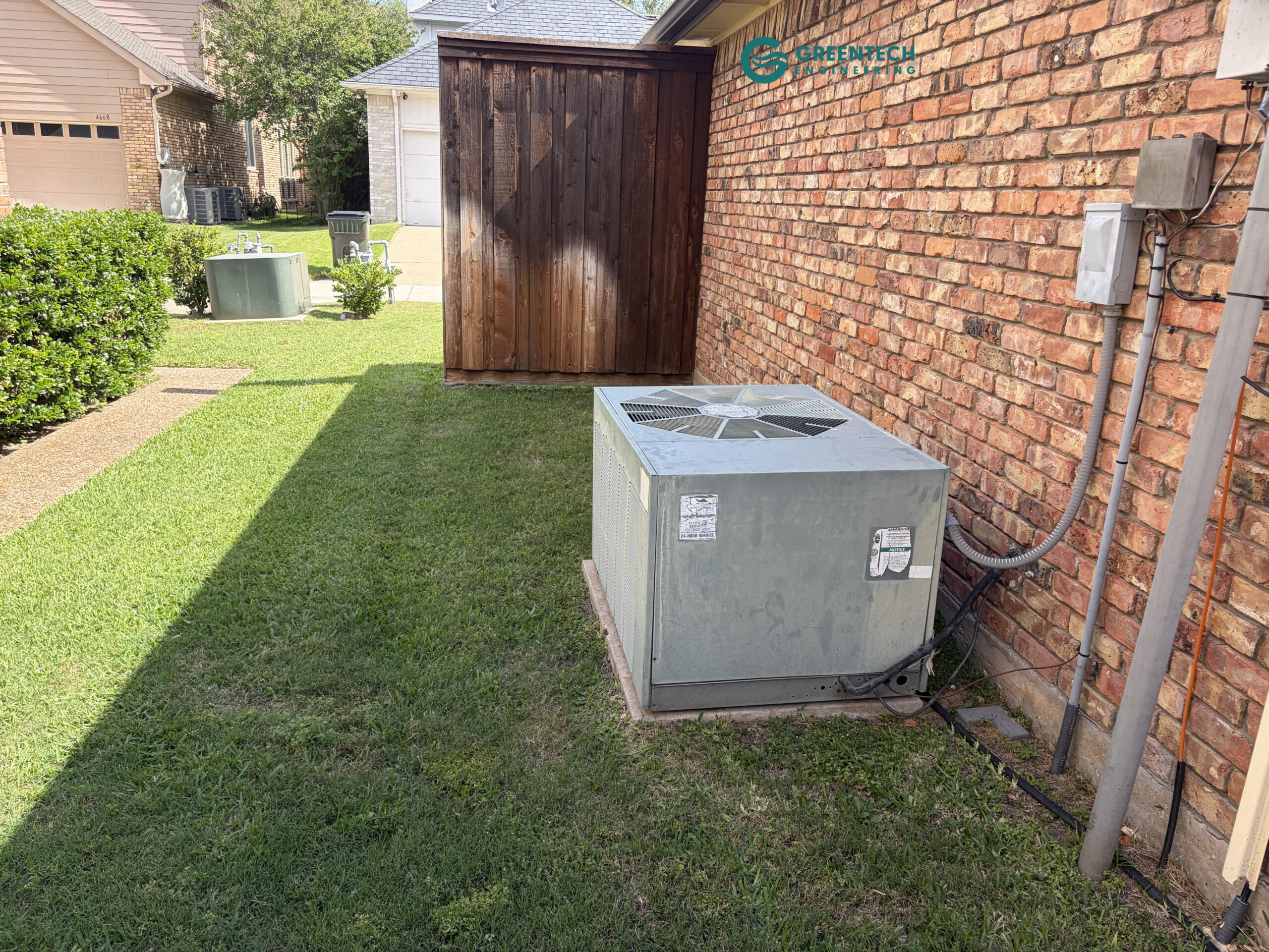 An aging, low-efficiency air conditioning condenser operating outside a brick home in Dallas, TX 75248, drawing excessive electrical current.
