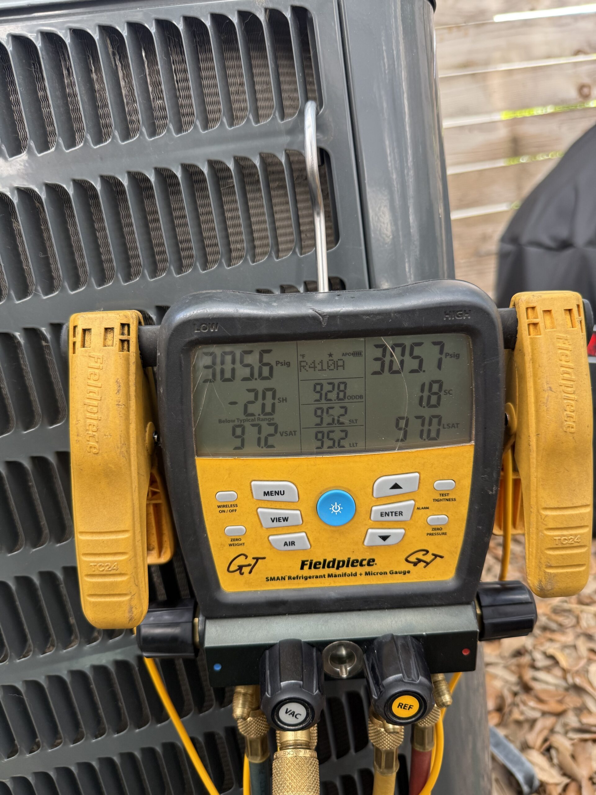 A digital Fieldpiece SMAN manifold gauge hooked up to a Dallas HVAC condenser, reading precise R-410A refrigerant pressures and saturation temperatures.