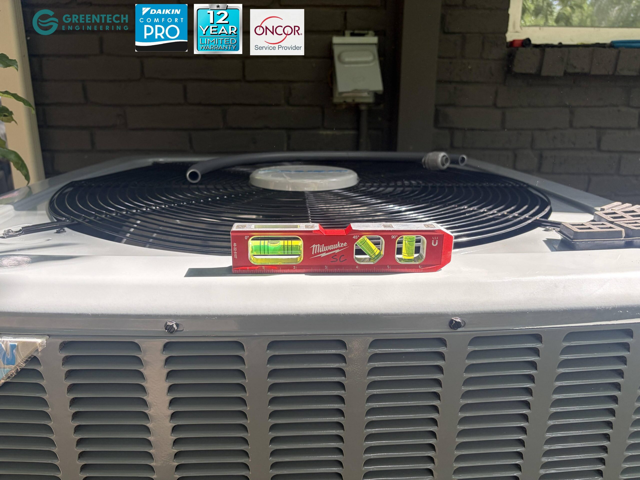 A red Milwaukee torpedo level resting on top of a newly installed Daikin condenser in Dallas, ensuring perfect horizontal alignment.