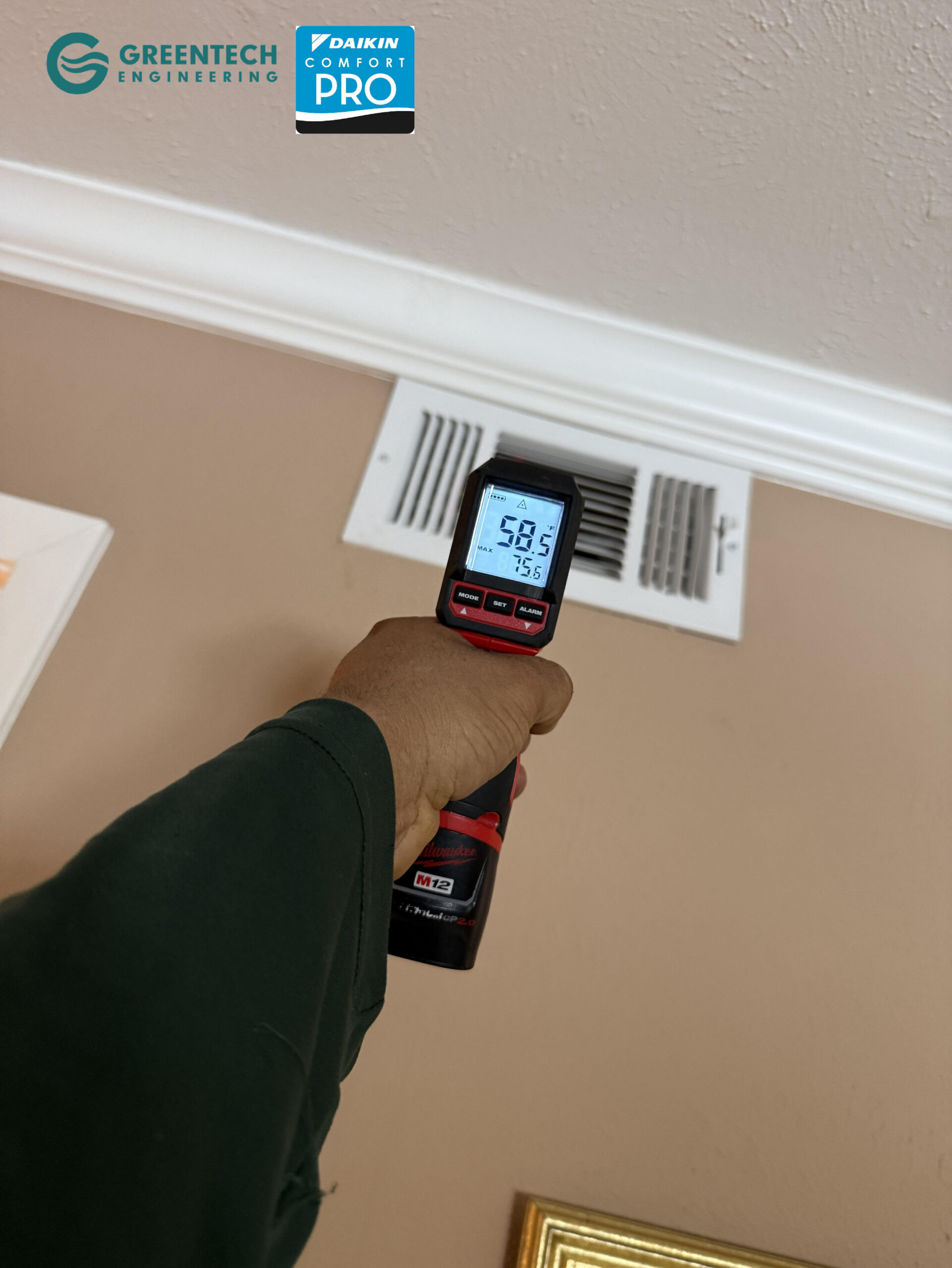 An HVAC technician holding a digital infrared thermometer pointing at an apartment ceiling vent, registering a frosty 58.5 degrees Fahrenheit.