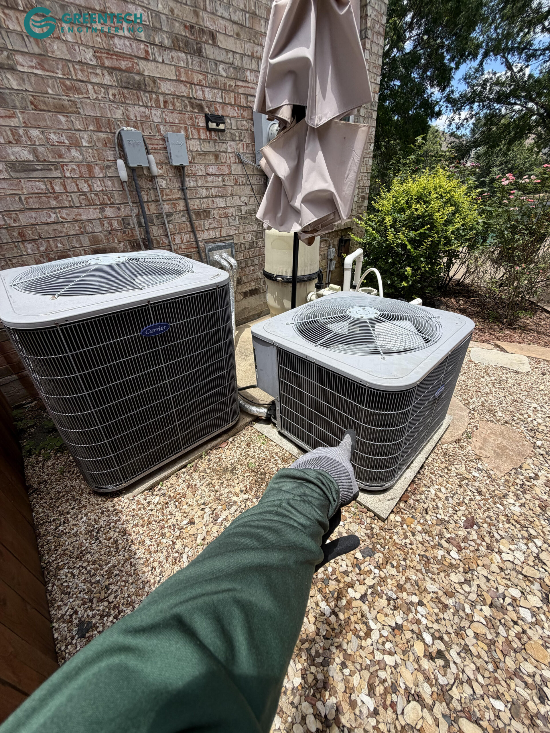An aging, low-efficiency Carrier air conditioning condenser sitting on a degraded pad outside a residential home in Dallas, Texas.