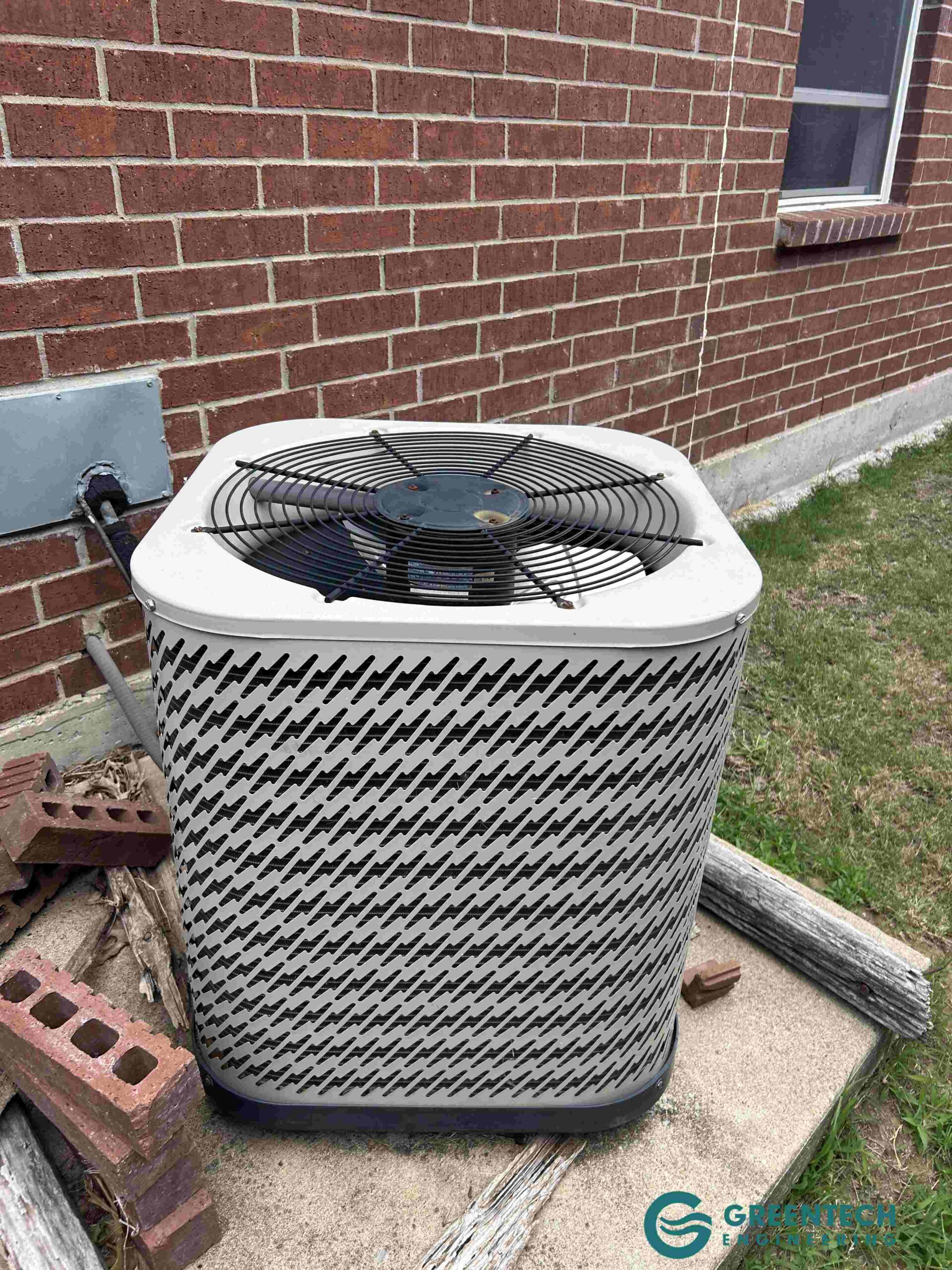An aging, inefficient central air conditioning condenser sitting on a black plastic pad outside a brick single-family home in Dallas, Texas 75248.