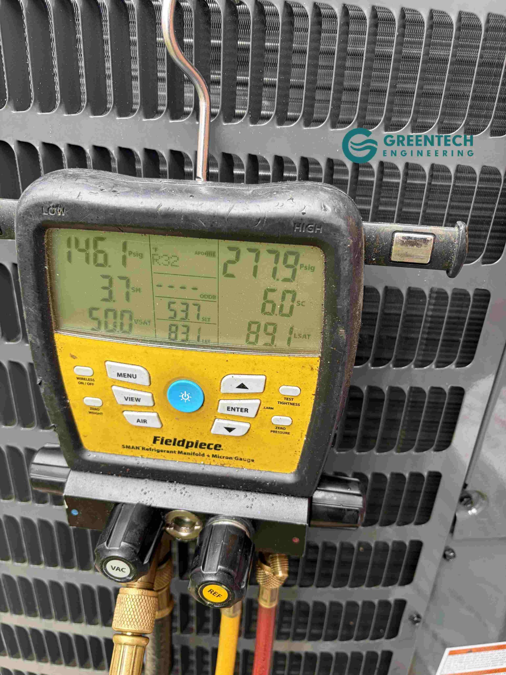 A Fieldpiece digital HVAC manifold gauge connected to the Goodman condenser, showing precise pressure and saturation temperatures.