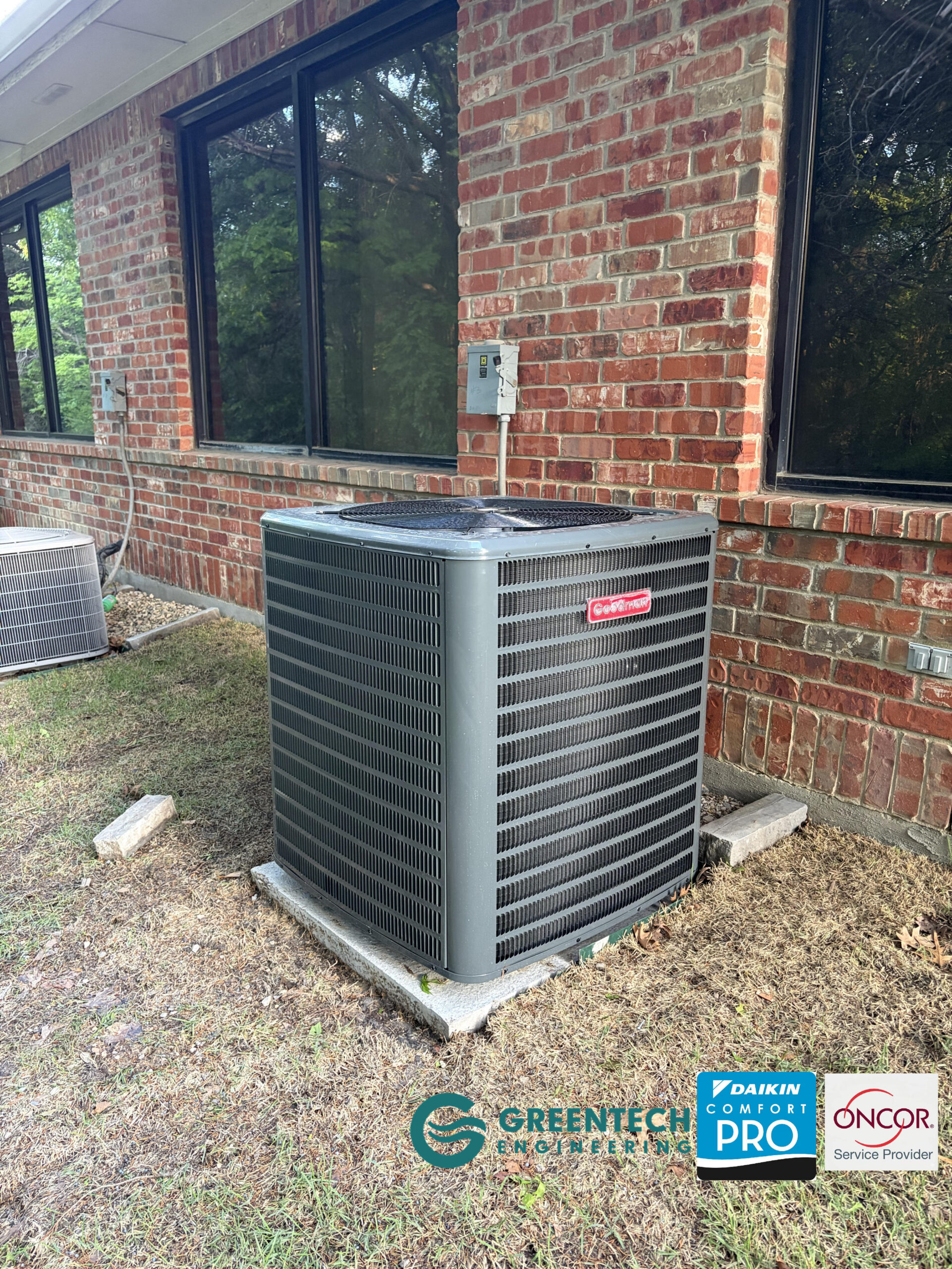 A newly installed, high-capacity commercial Goodman split-system AC condenser sitting securely outside a Dallas brick office building.