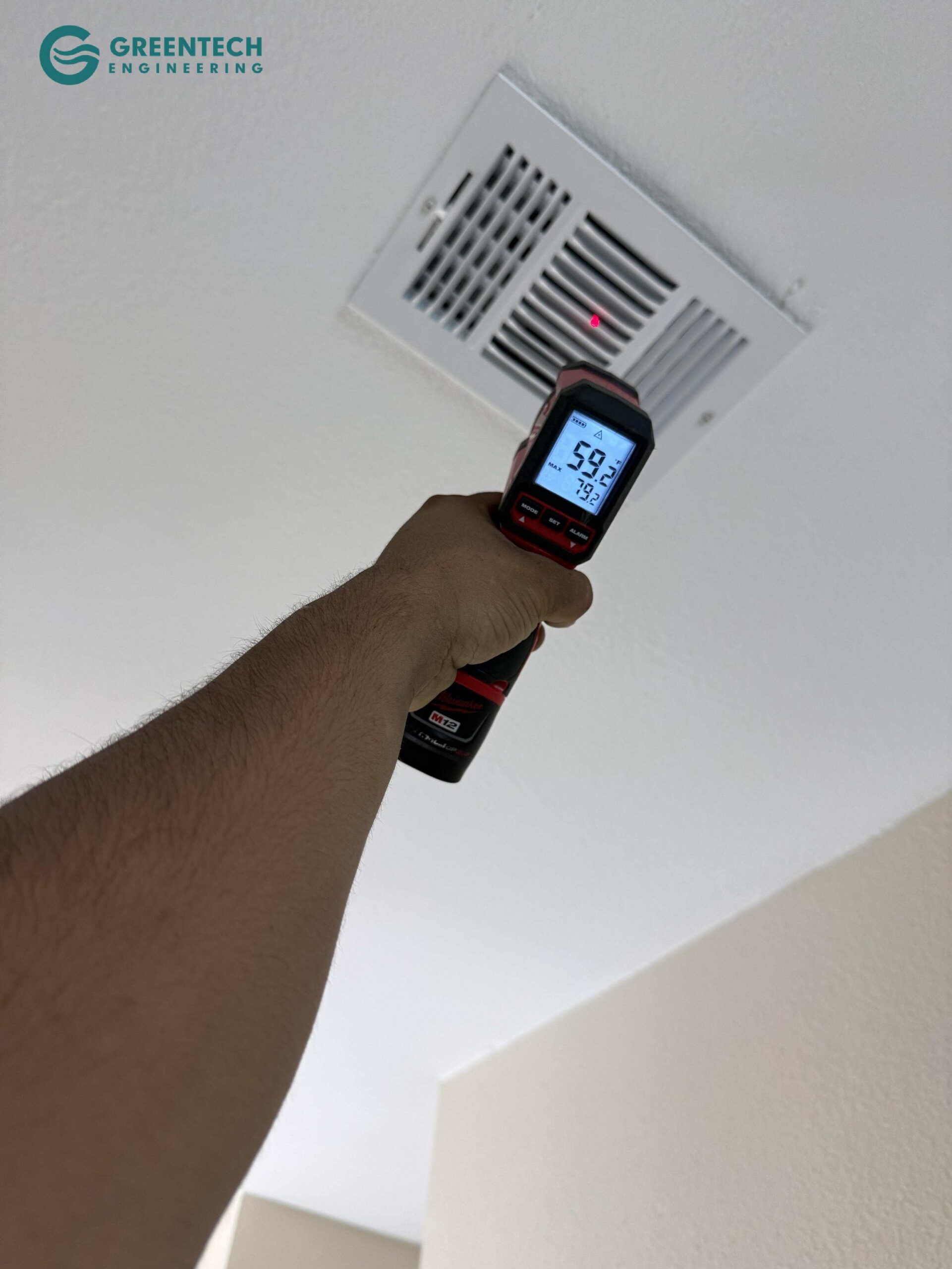 An HVAC technician holding a Milwaukee digital infrared thermometer pointing at a ceiling air vent, registering a frosty 59.2 degrees Fahrenheit supply air temperature.
