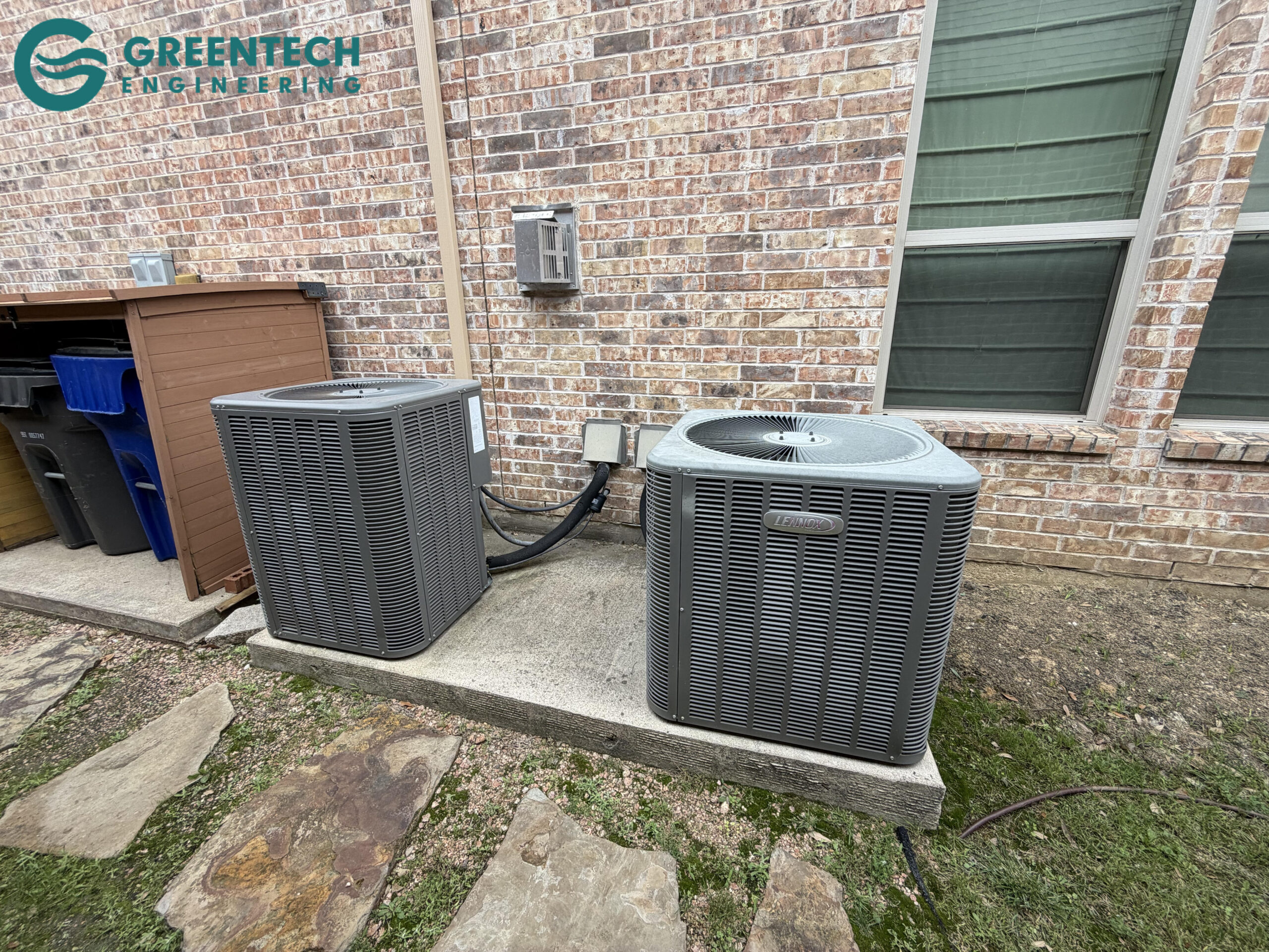 Two old, inefficient, and mismatched Lennox air conditioning condensers sitting on a concrete pad outside a brick house in Dallas 75248.