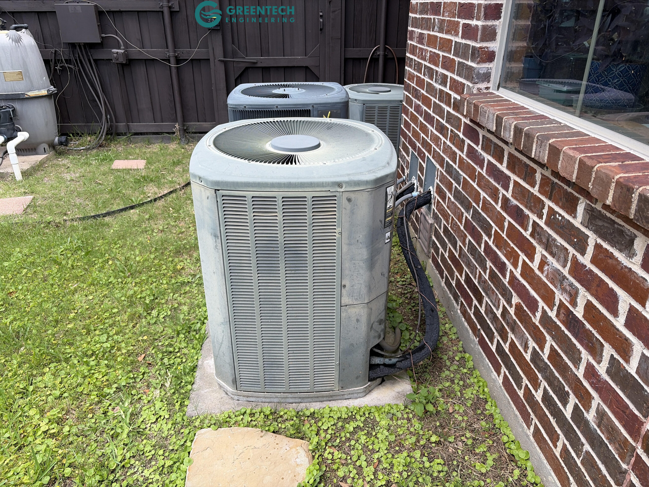 Two aging, oversized 4-Ton air conditioning condensers sitting outside a brick two-story home in Allen, Texas 75013.