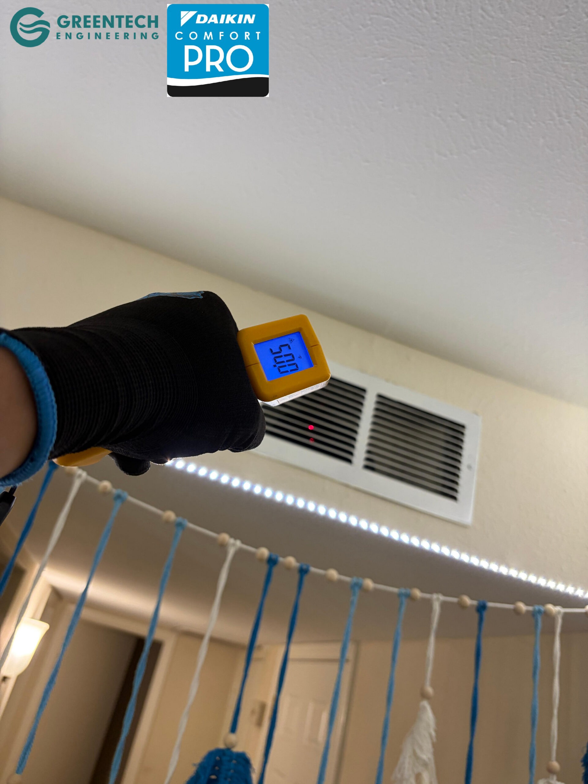 A digital infrared thermometer pointing at a ceiling air vent inside a Forney apartment, registering a frosty 50.0 degrees Fahrenheit.