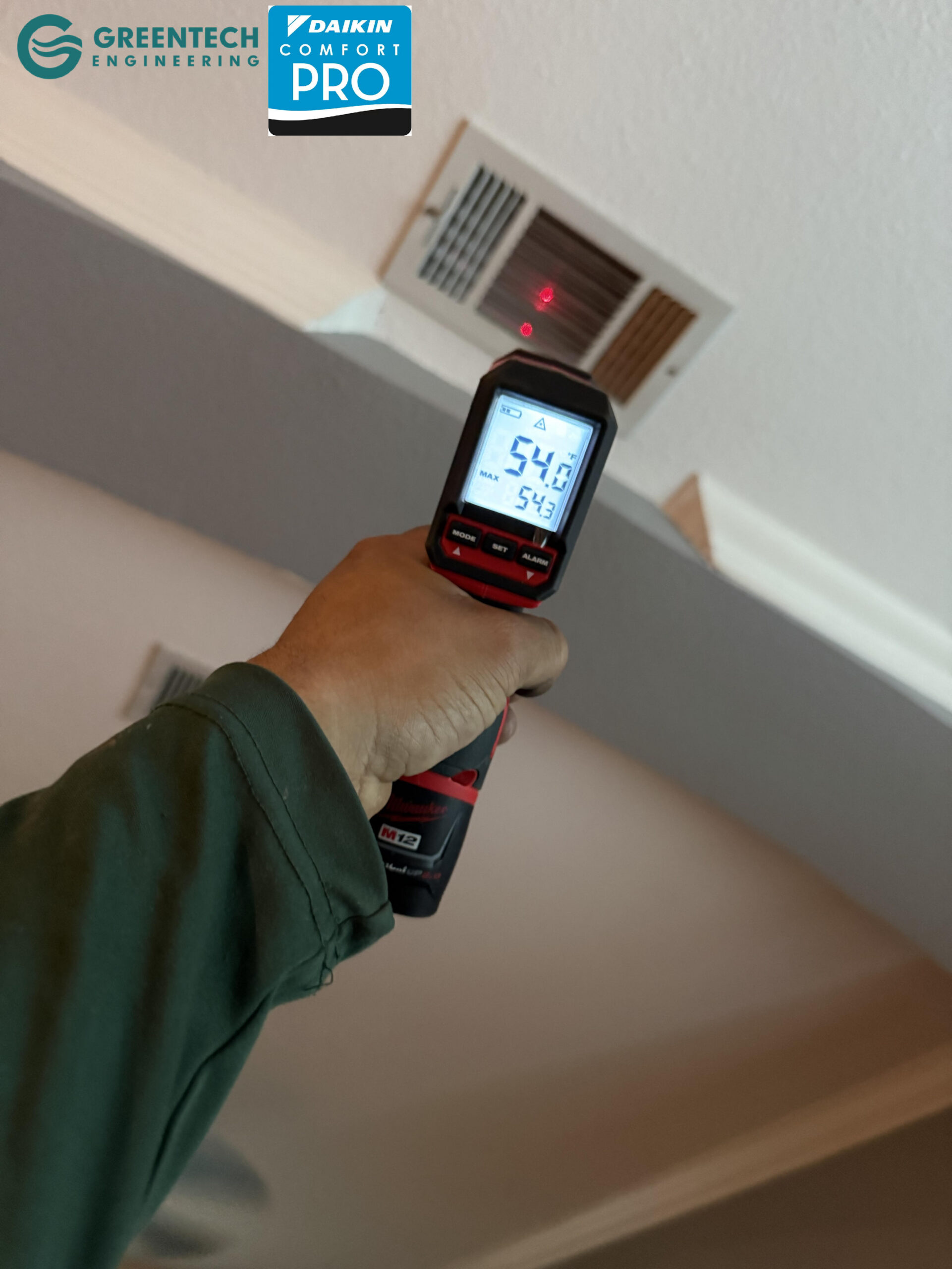 An HVAC technician using a digital infrared thermometer to measure the supply air temperature from a ceiling vent in a Forney home.