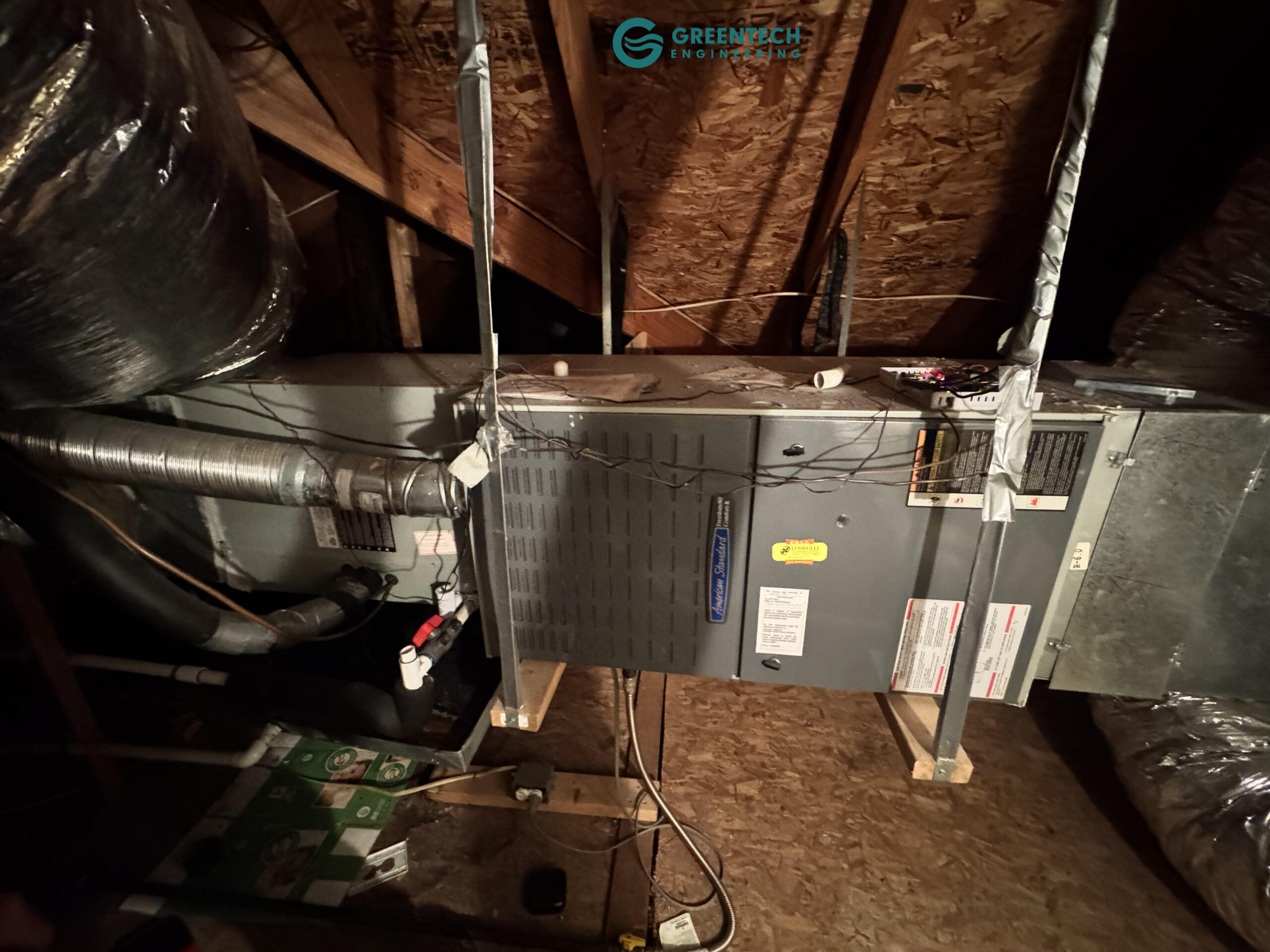 An older American Standard indoor HVAC air handler and furnace installed horizontally in a residential attic.