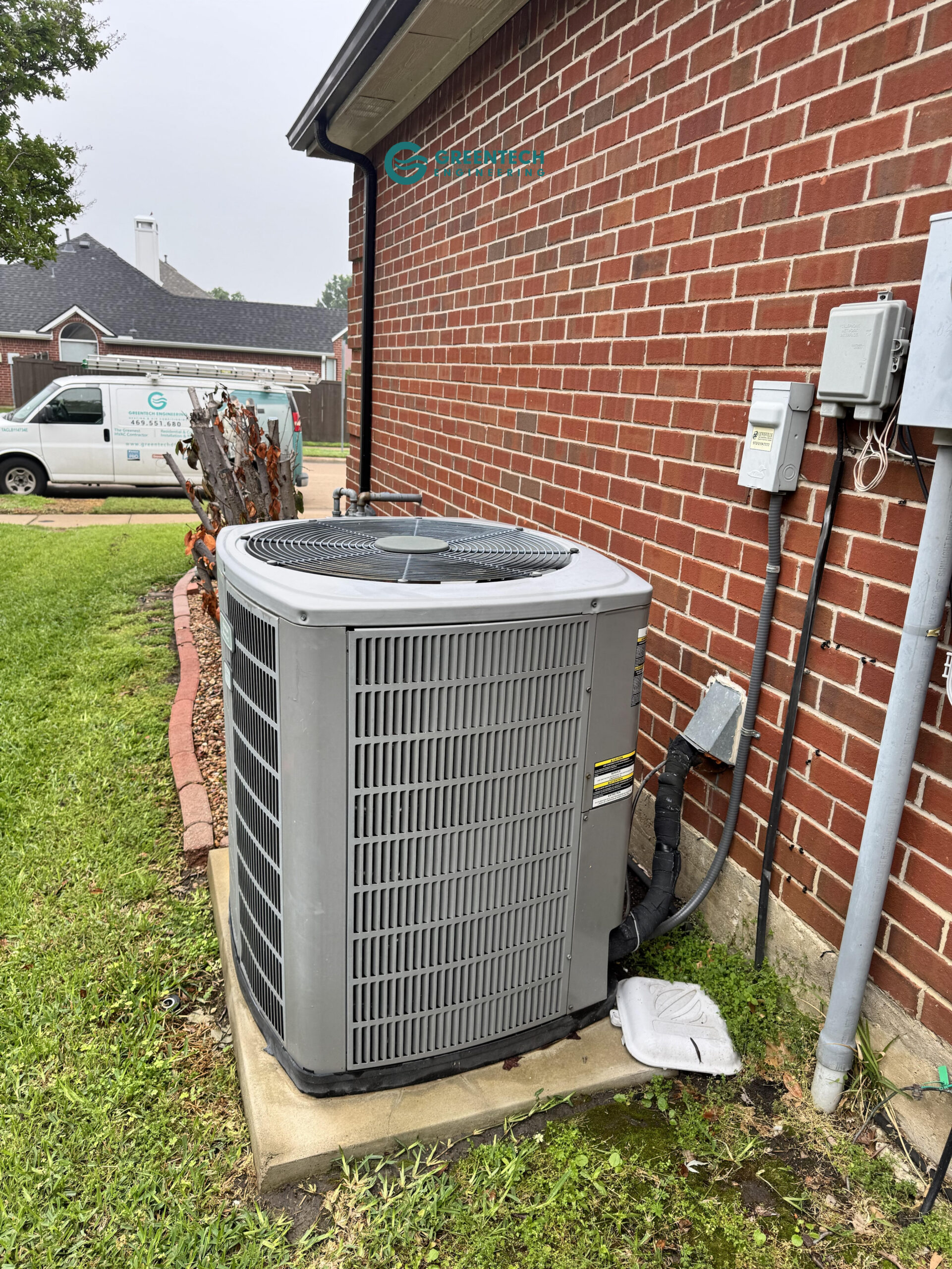 An aging, inefficient air conditioning condenser sitting on a concrete pad outside a brick home in Forney, Texas.