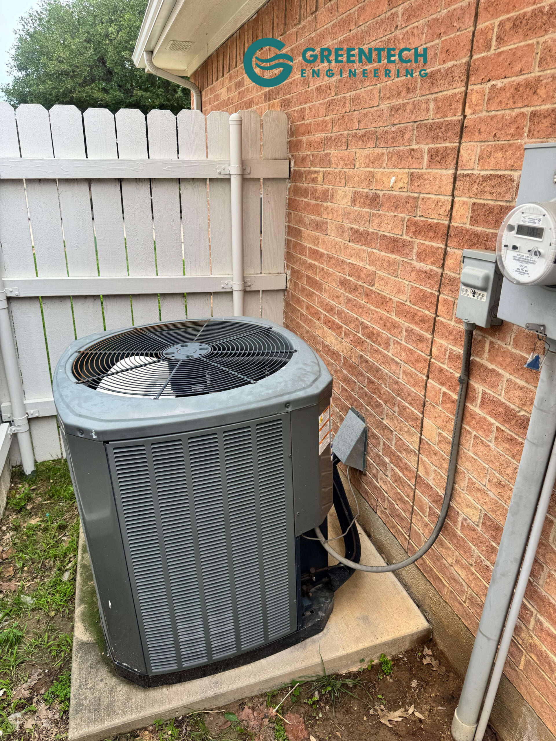 An aging, inefficient central air conditioning condenser sitting outside a brick two-story home in Fort Worth, Texas 76179.