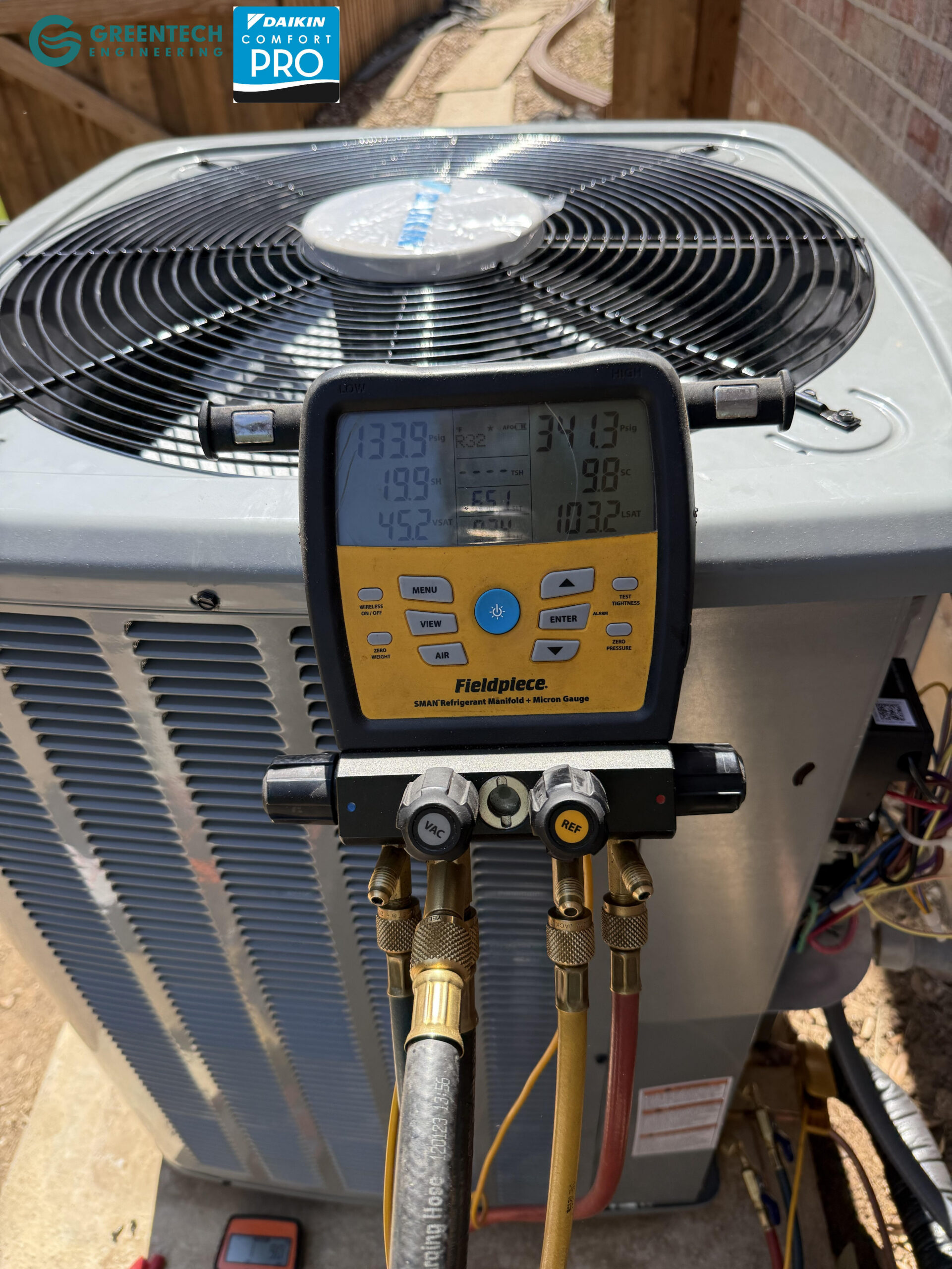 Greentech Engineering technician using a Fieldpiece digital manifold gauge to perform a vacuum and pressure test on a new Daikin AC in Frisco, TX.