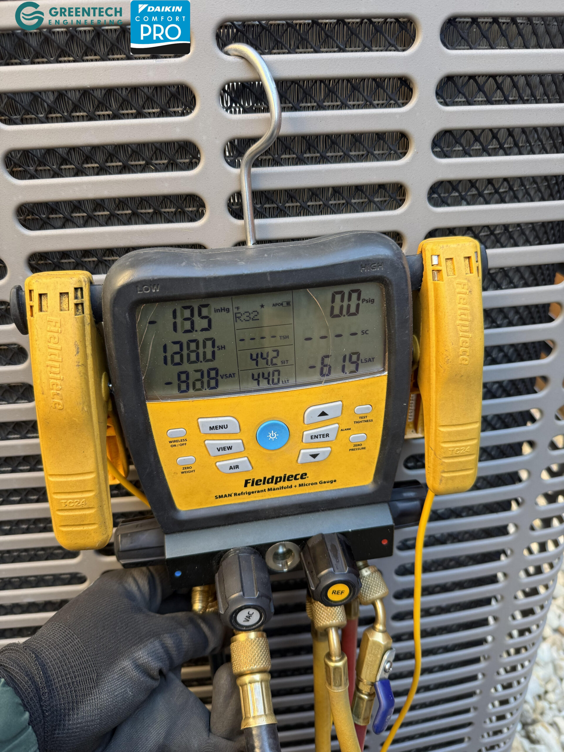 Fieldpiece digital manifold gauge attached to a new Daikin air conditioning condenser, displaying refrigerant pressures and temperatures.