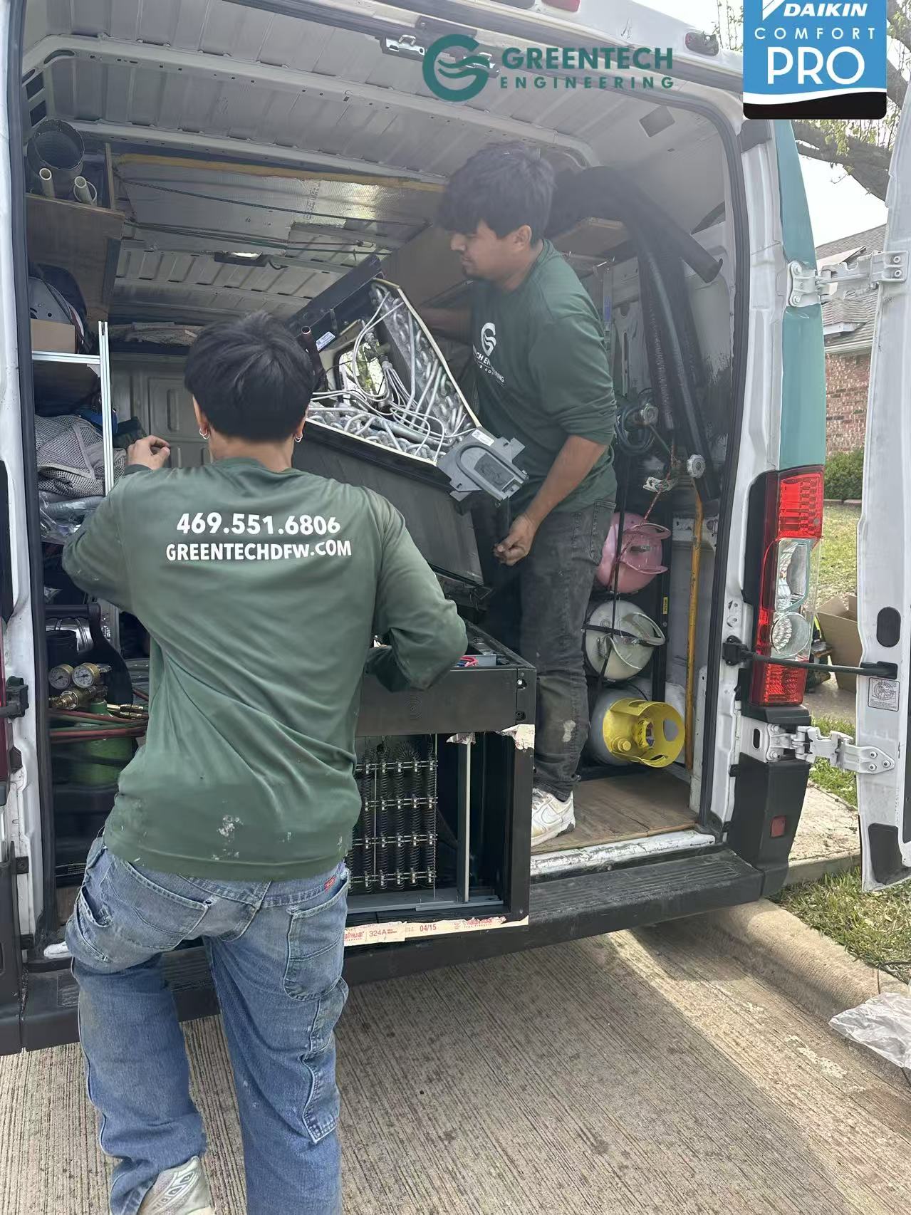 Greentech Engineering technicians loading an old, inefficient HVAC evaporator coil into a company van during an AC to heat pump conversion.