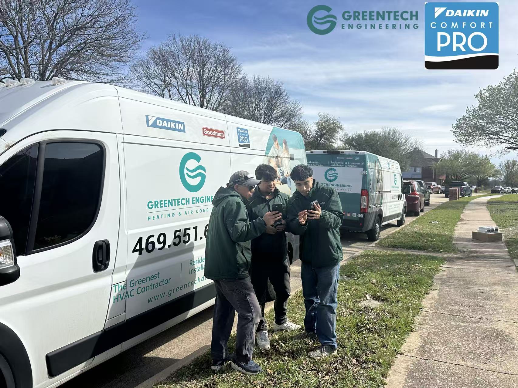  Greentech Engineering installation team reviewing smart thermostat controls and Daikin system diagnostics on their mobile devices next to company vans.