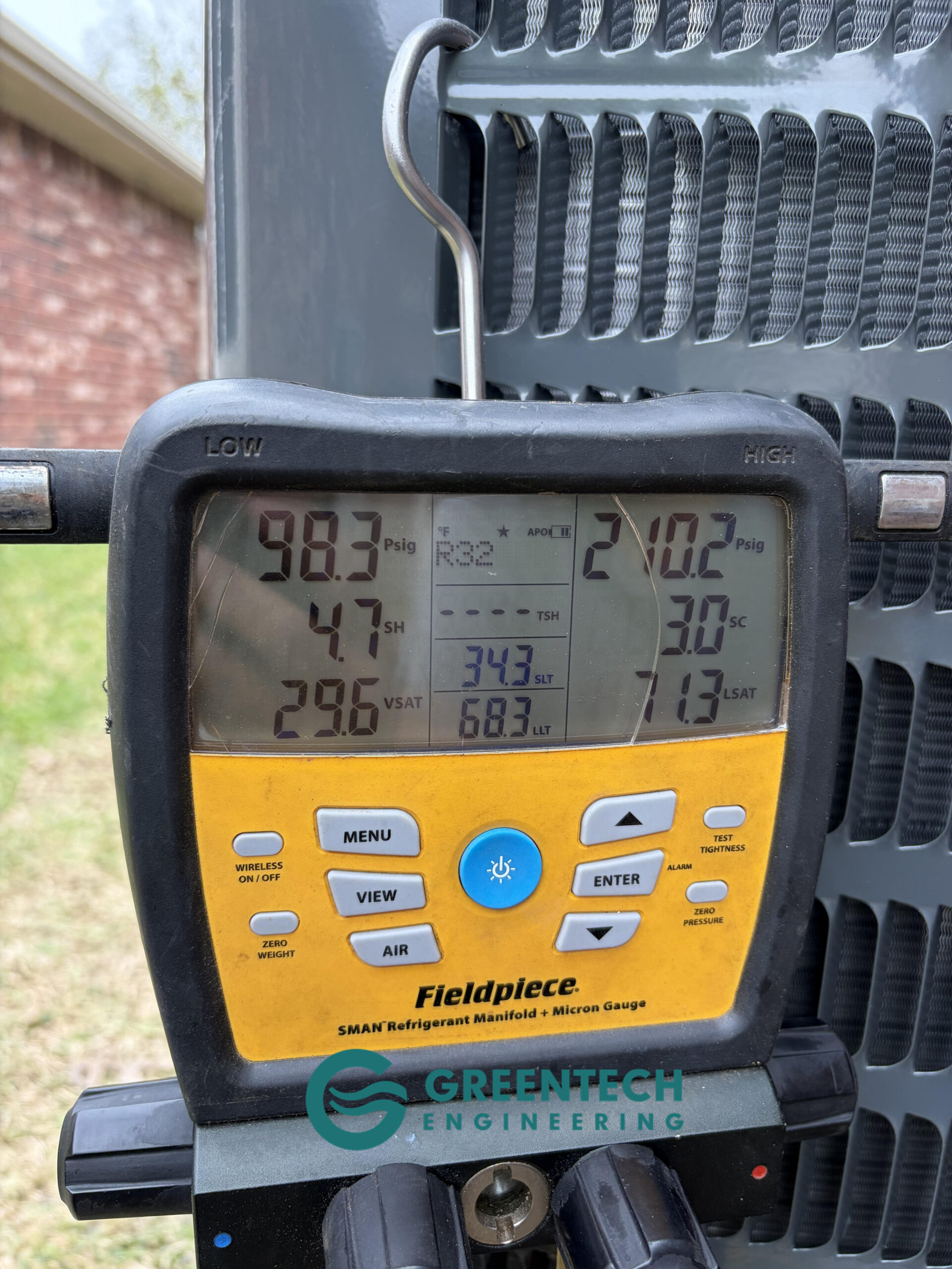 Greentech Engineering technician using a Fieldpiece digital manifold gauge to perform a sub-500 micron vacuum test on a new Goodman AC in Grand Prairie, TX.