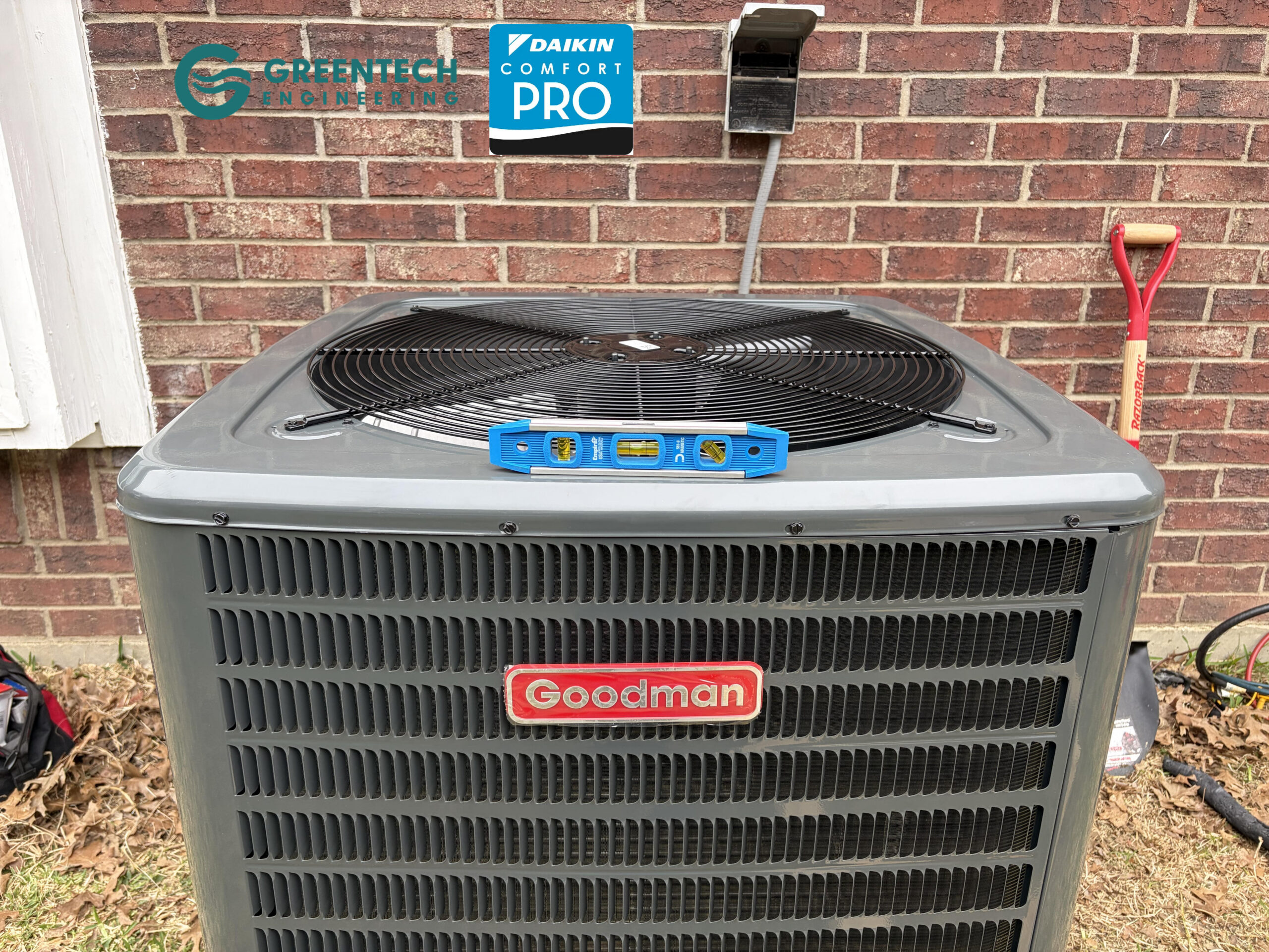 A precision spirit level sitting on top of a newly installed Goodman AC condenser to ensure perfect balance on a concrete pad.