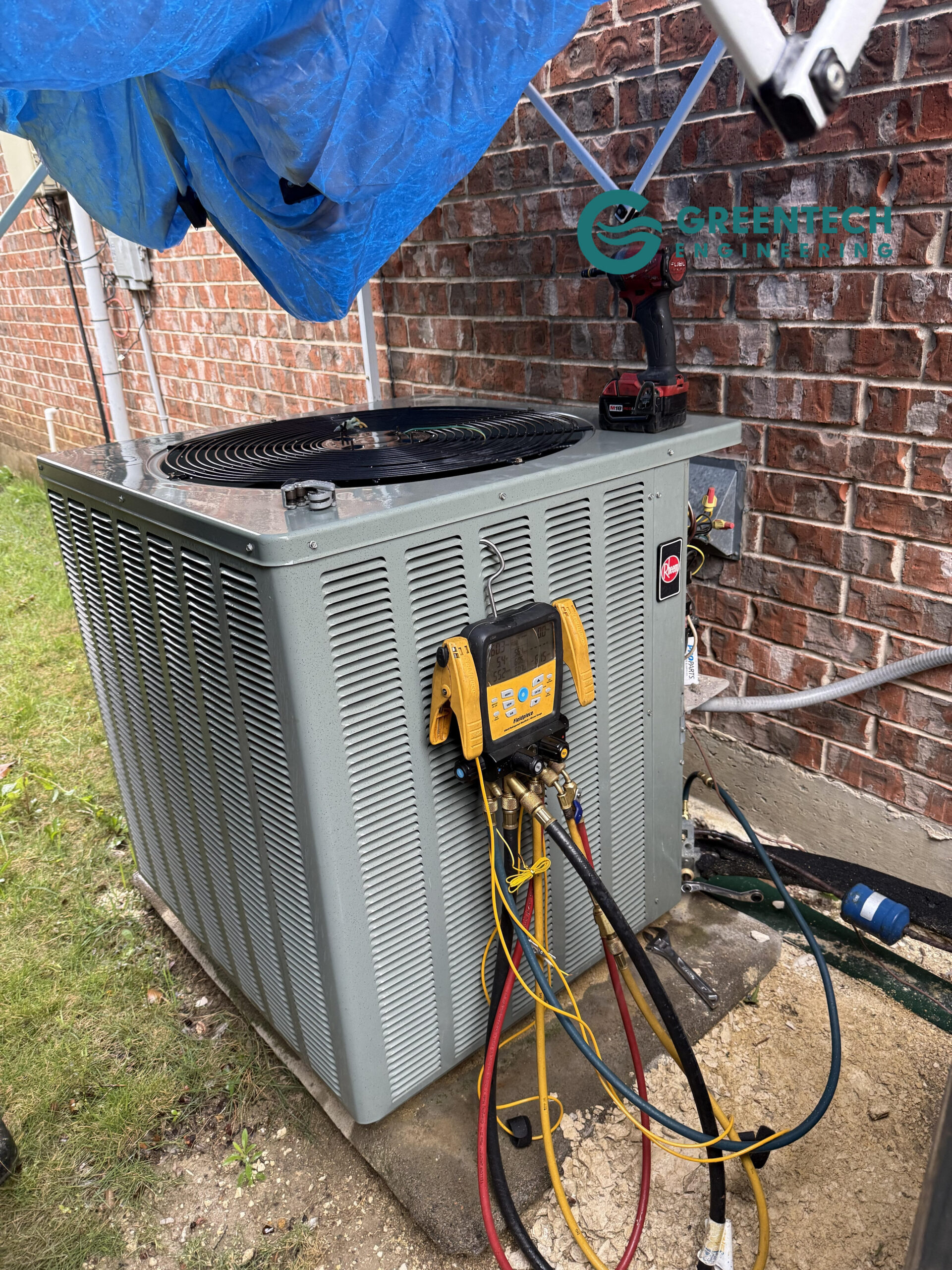 A Greentech Engineering technician uses digital manifold gauges to diagnose a failed builder-grade Rheem AC condenser under a protective tarp in Forney, TX 75126.