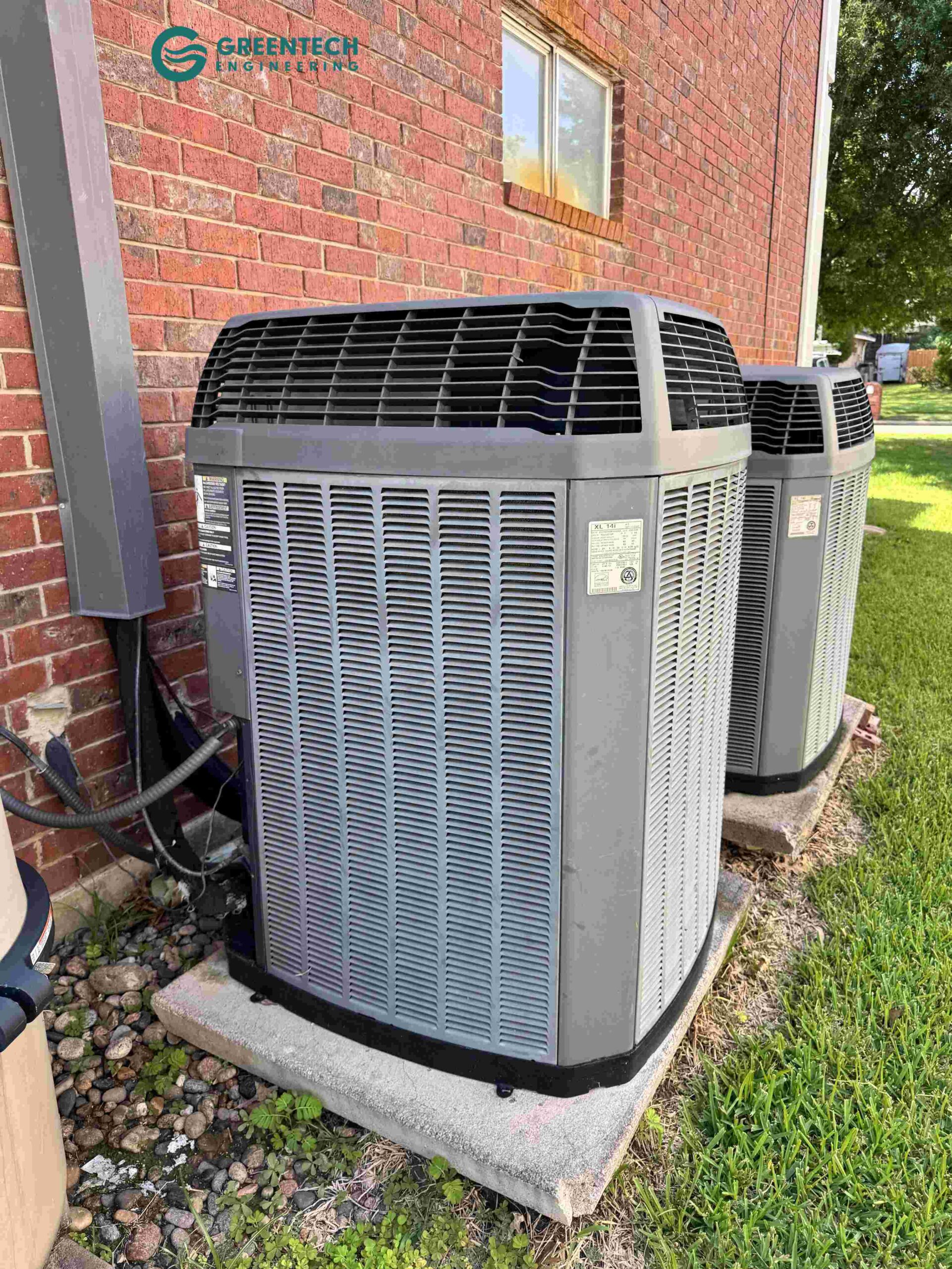 Two aging, low-efficiency air conditioning condensers sitting outside a residential brick home in Plano, Texas.