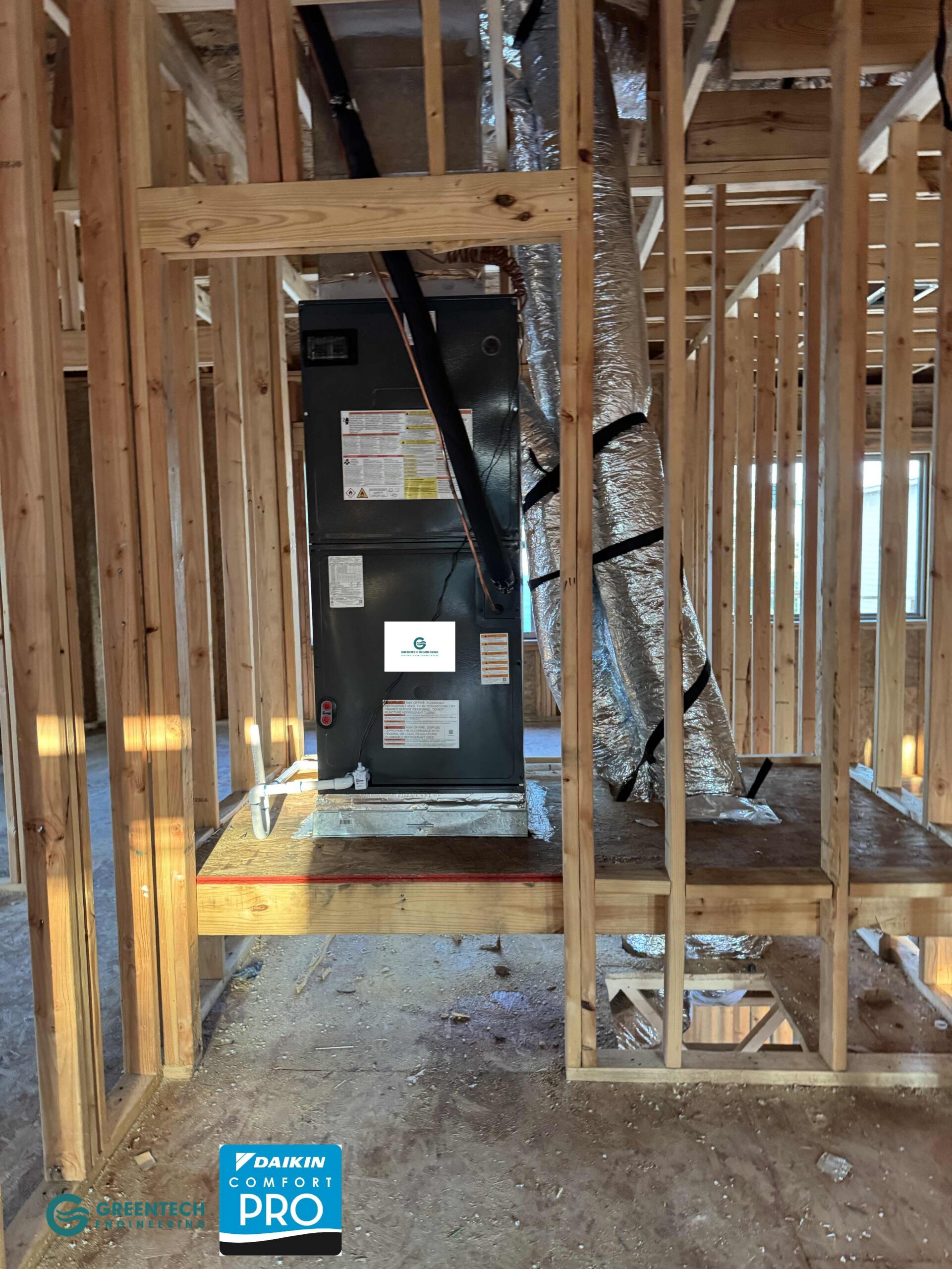  A vertically installed indoor HVAC air handler unit sitting on a custom wooden platform within the framing of a new construction home in Plano, TX.