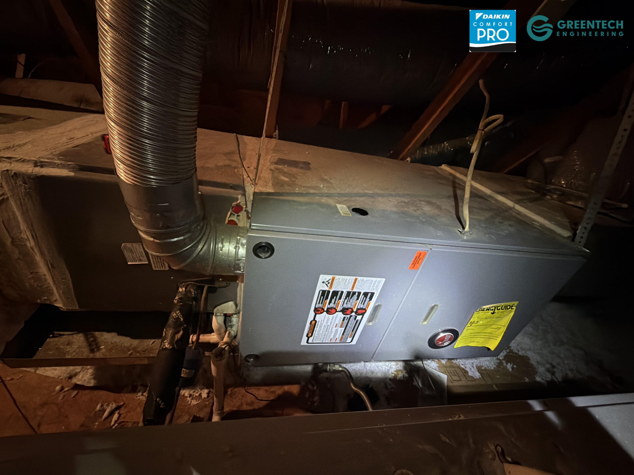An old, inefficient Rheem gas furnace and evaporator coil installed in a dark residential attic in Plano, showing signs of aging ductwork.