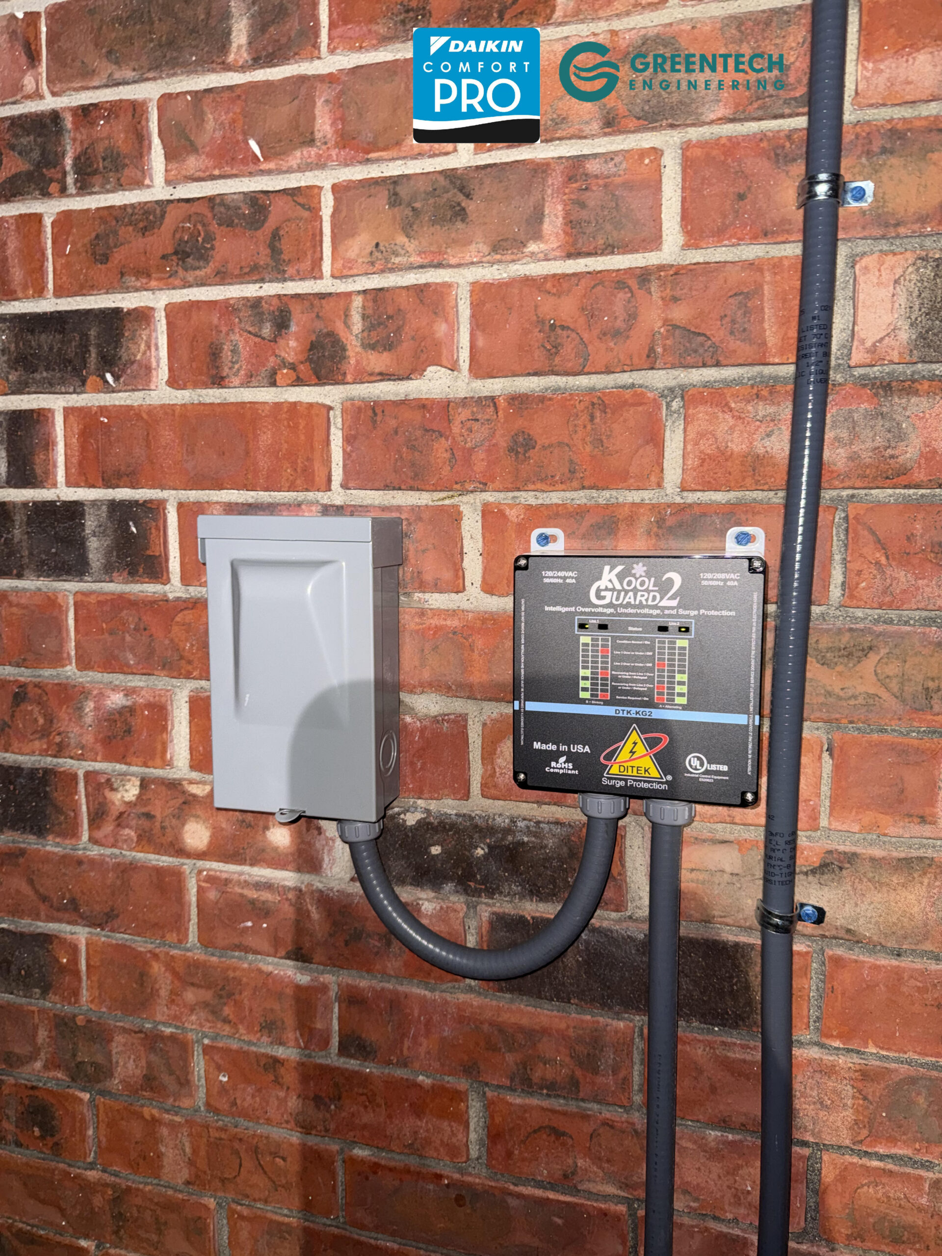 A Ditek Kool Guard 2 surge protector and voltage monitor installed next to a gray electrical disconnect box on a brick exterior wall.