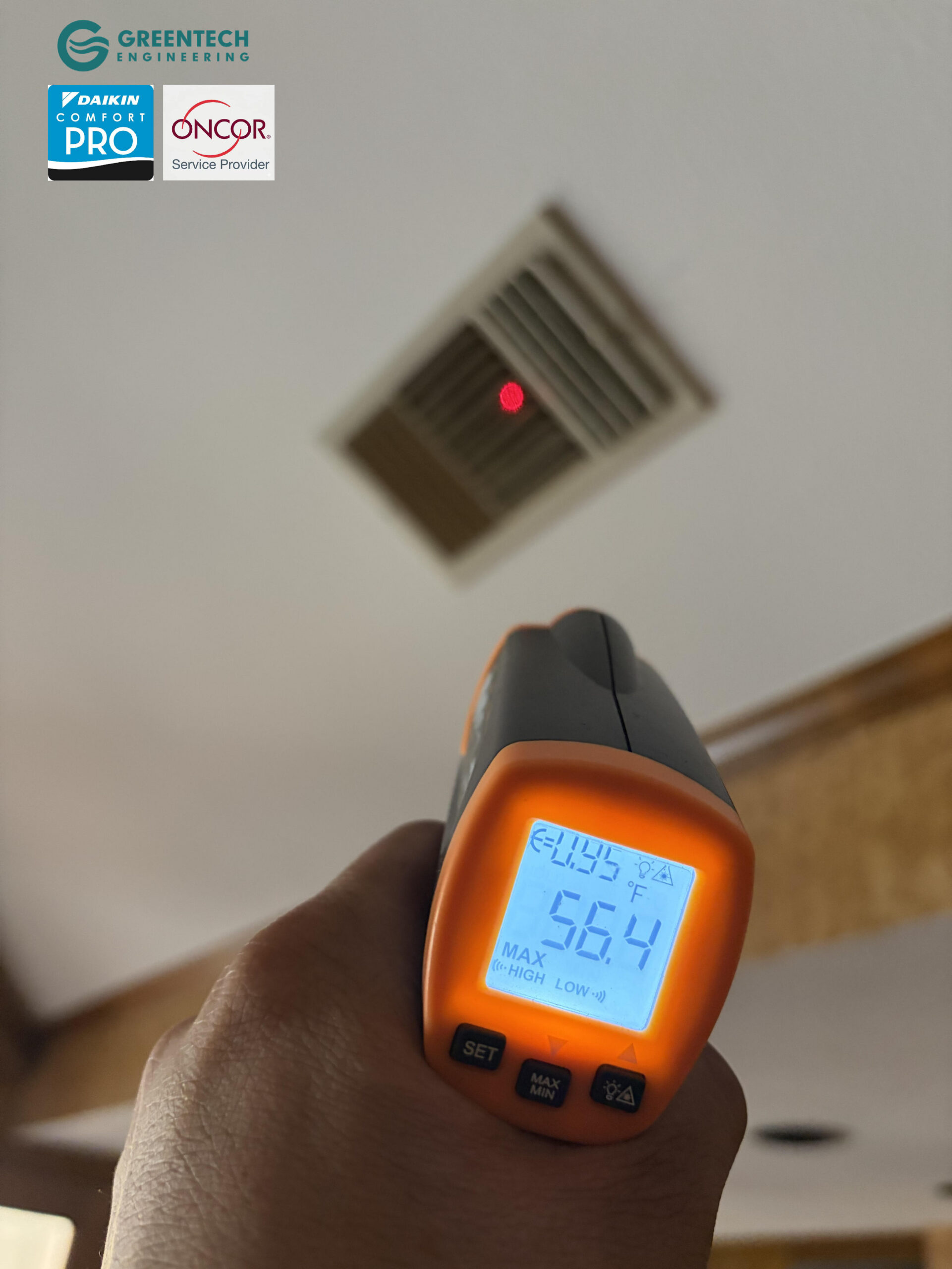 A hand holding a digital infrared thermometer pointing at a ceiling HVAC vent, displaying a freezing supply air temperature of 56.4°F.