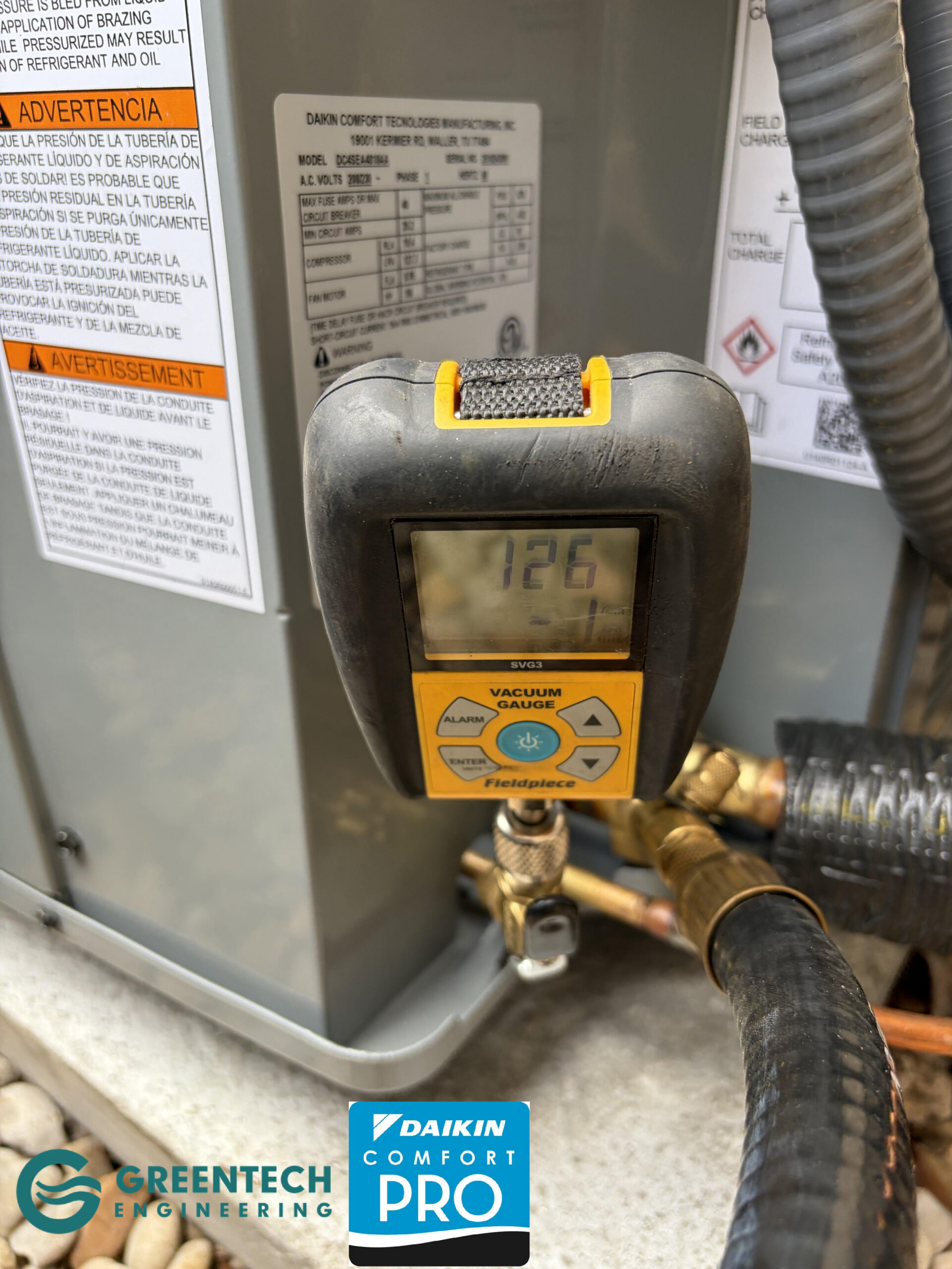 A Fieldpiece digital HVAC vacuum micron gauge attached to copper refrigerant lines, displaying a highly precise reading of 126 microns.