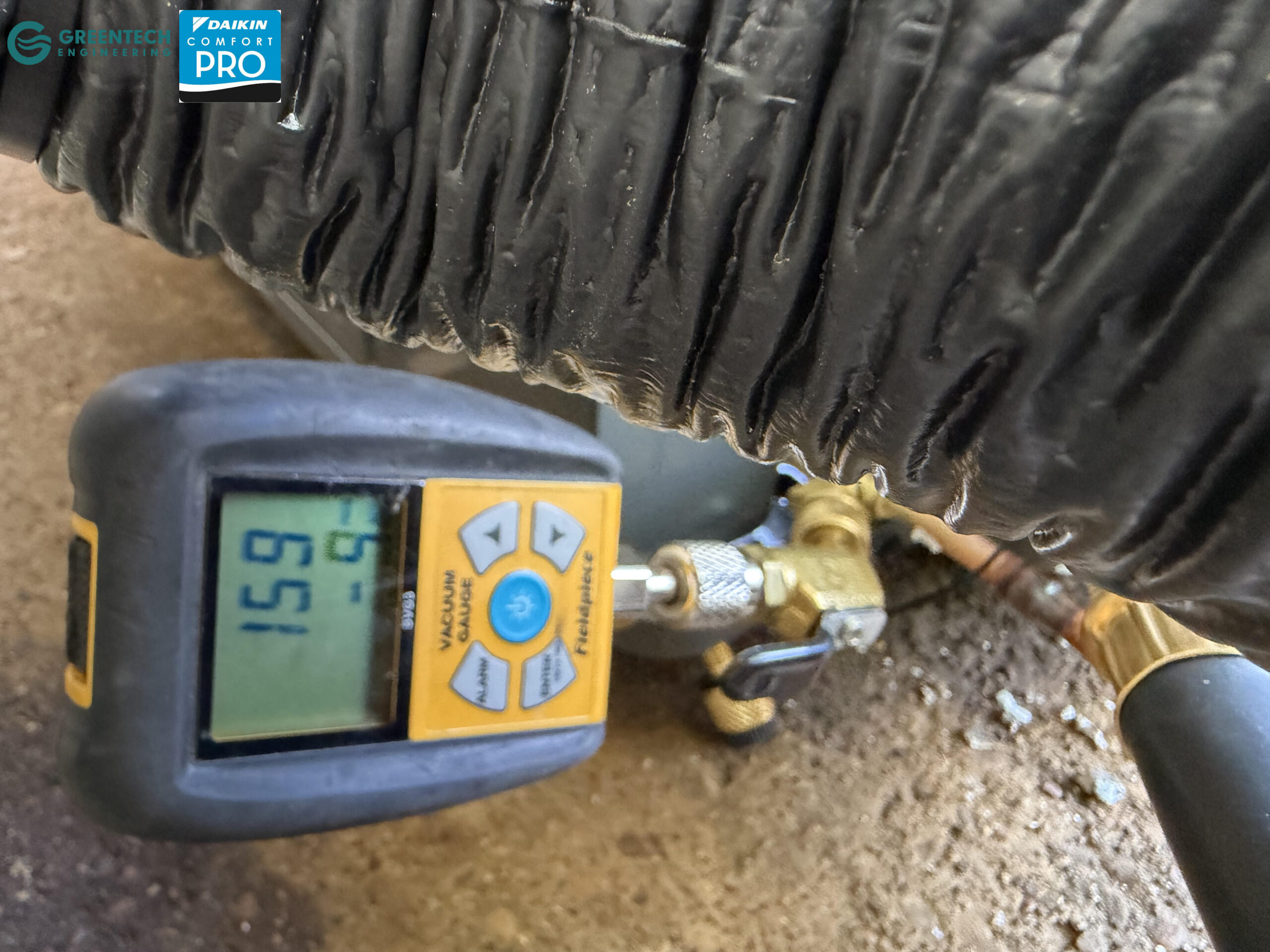 A Fieldpiece digital vacuum micron gauge attached to copper refrigerant lines, displaying a highly precise reading of 159 microns.